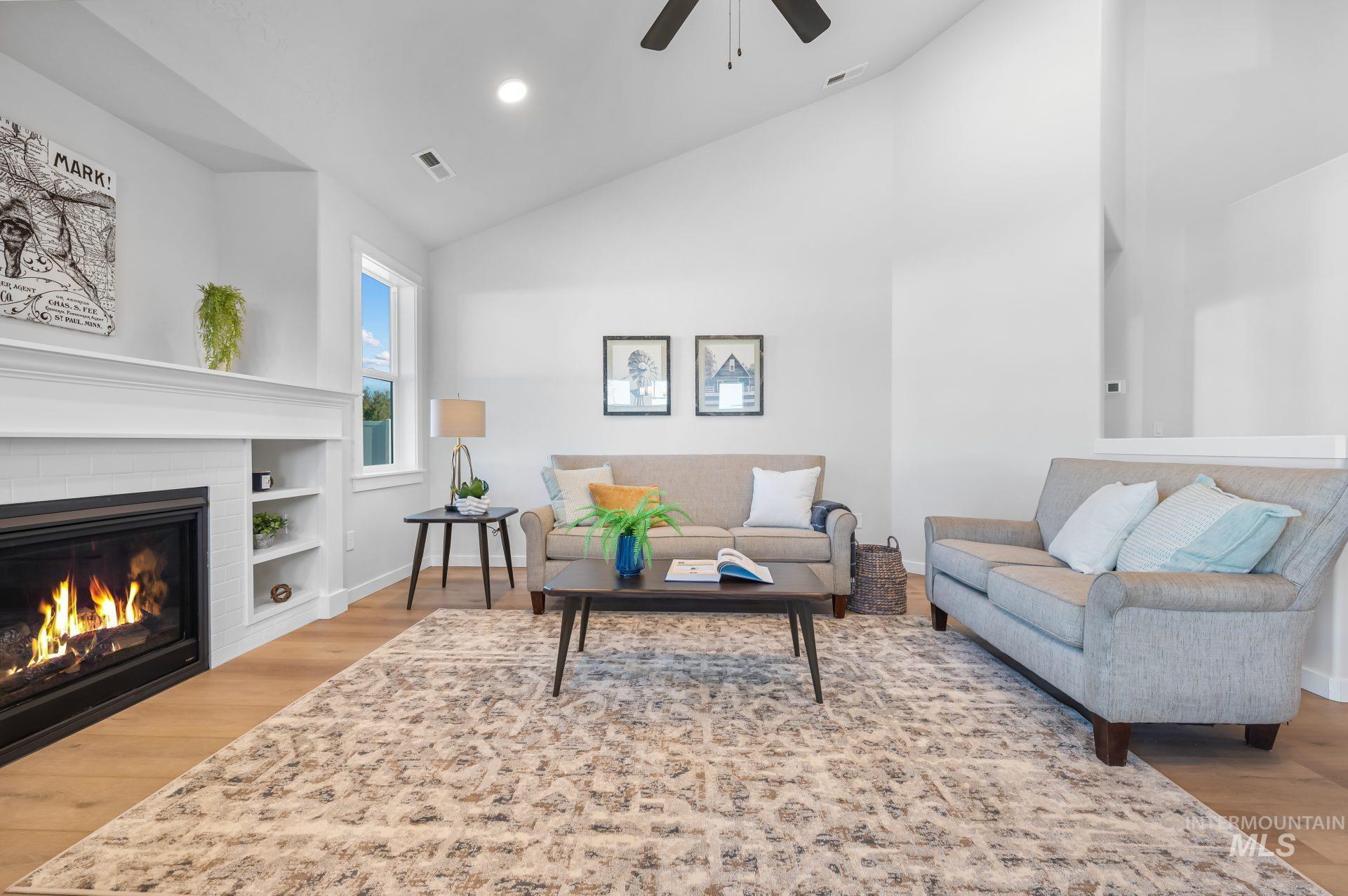Living room with light wood finished floors, high vaulted ceiling, a glass covered fireplace, ceiling fan, and recessed lighting