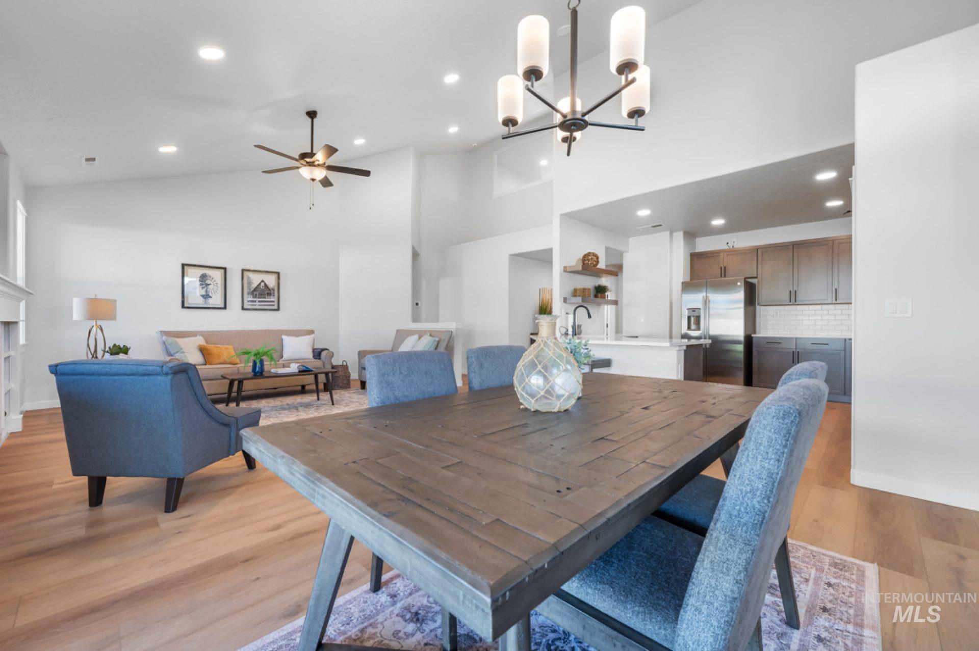 Dining room with high vaulted ceiling, light wood finished floors, recessed lighting, ceiling fan, and a chandelier