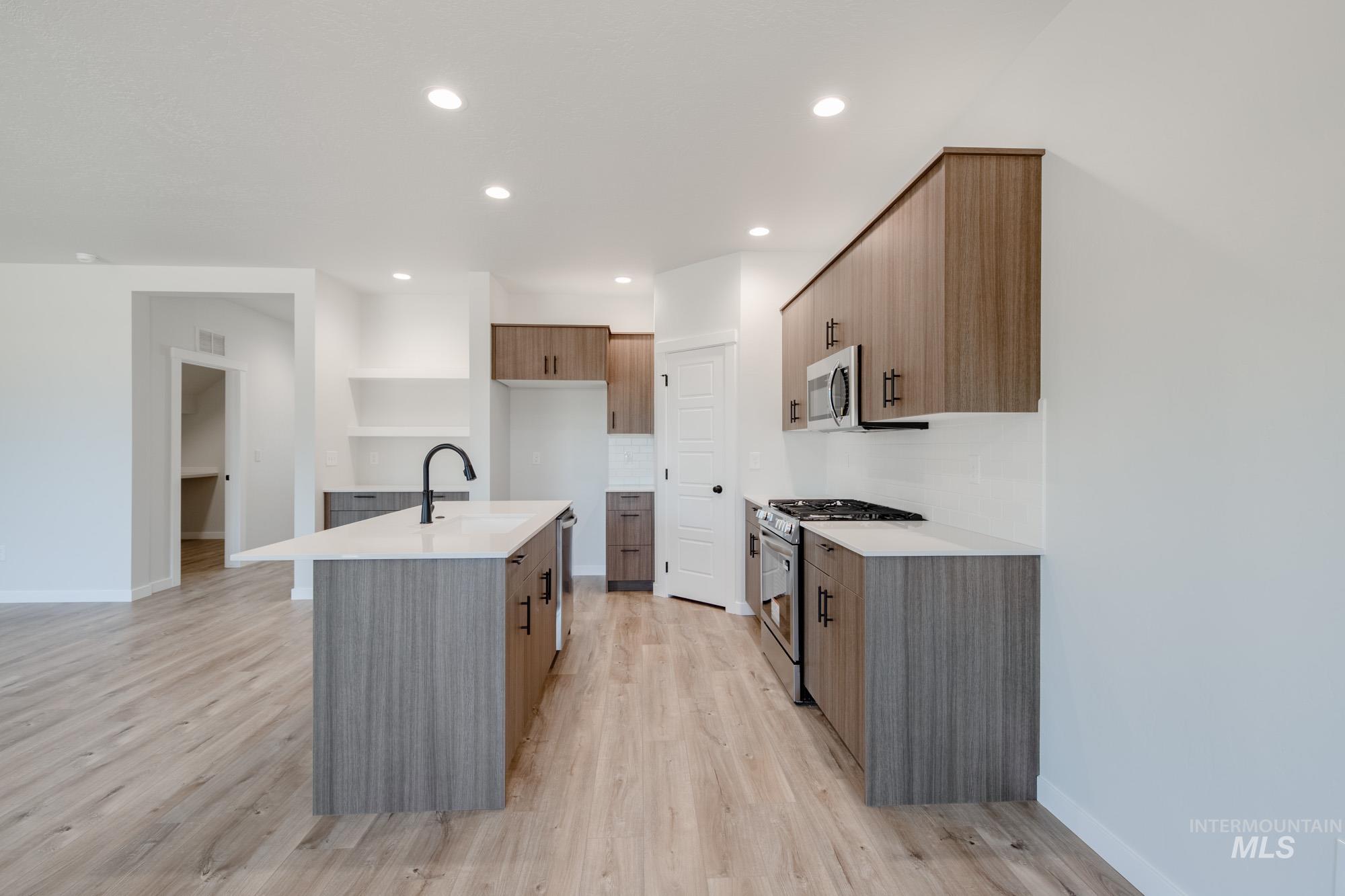 Kitchen with stainless steel appliances, light wood-type flooring, light countertops, and recessed lighting