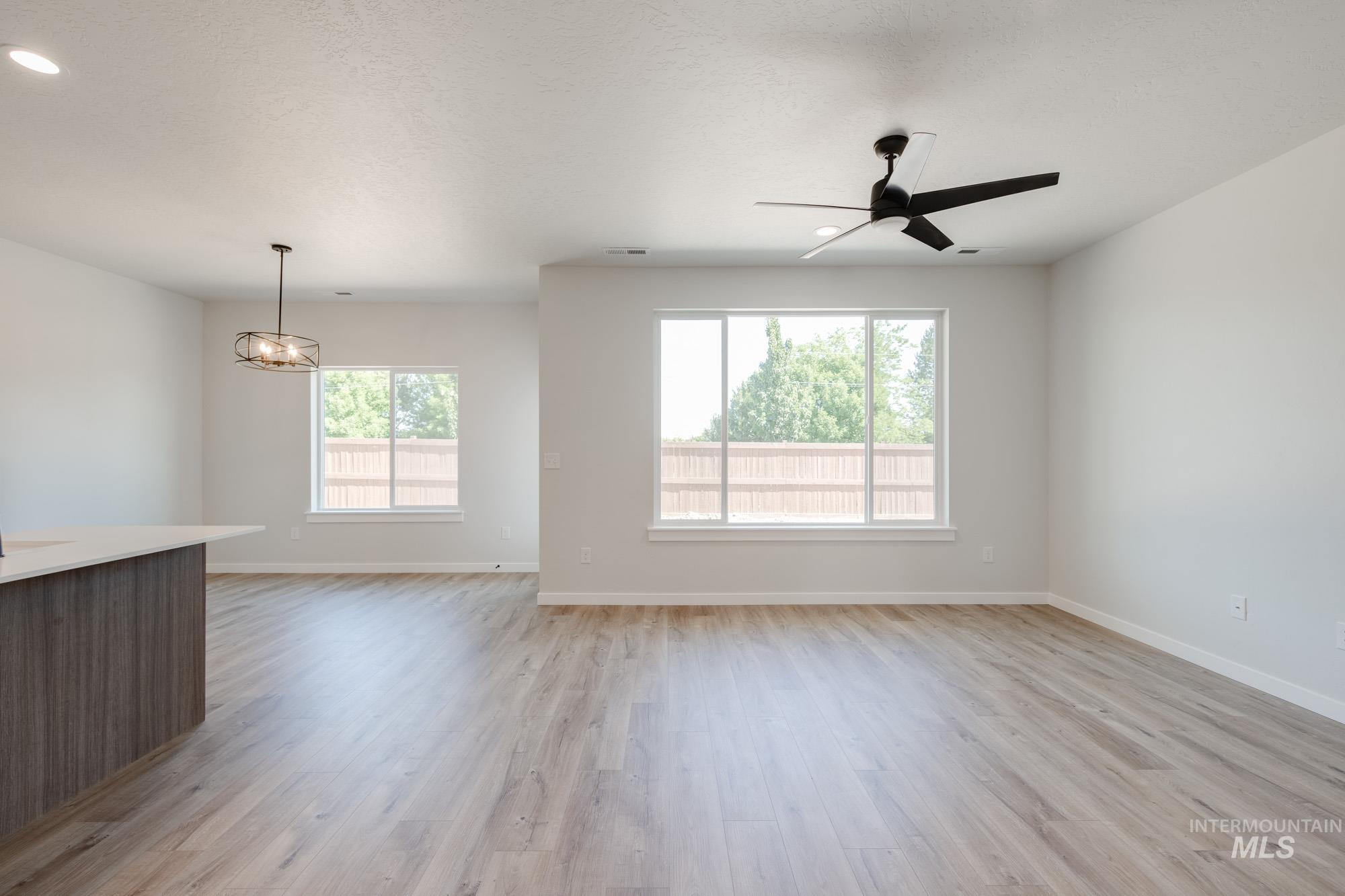 Unfurnished living room with light wood-style floors, a chandelier, ceiling fan, and recessed lighting