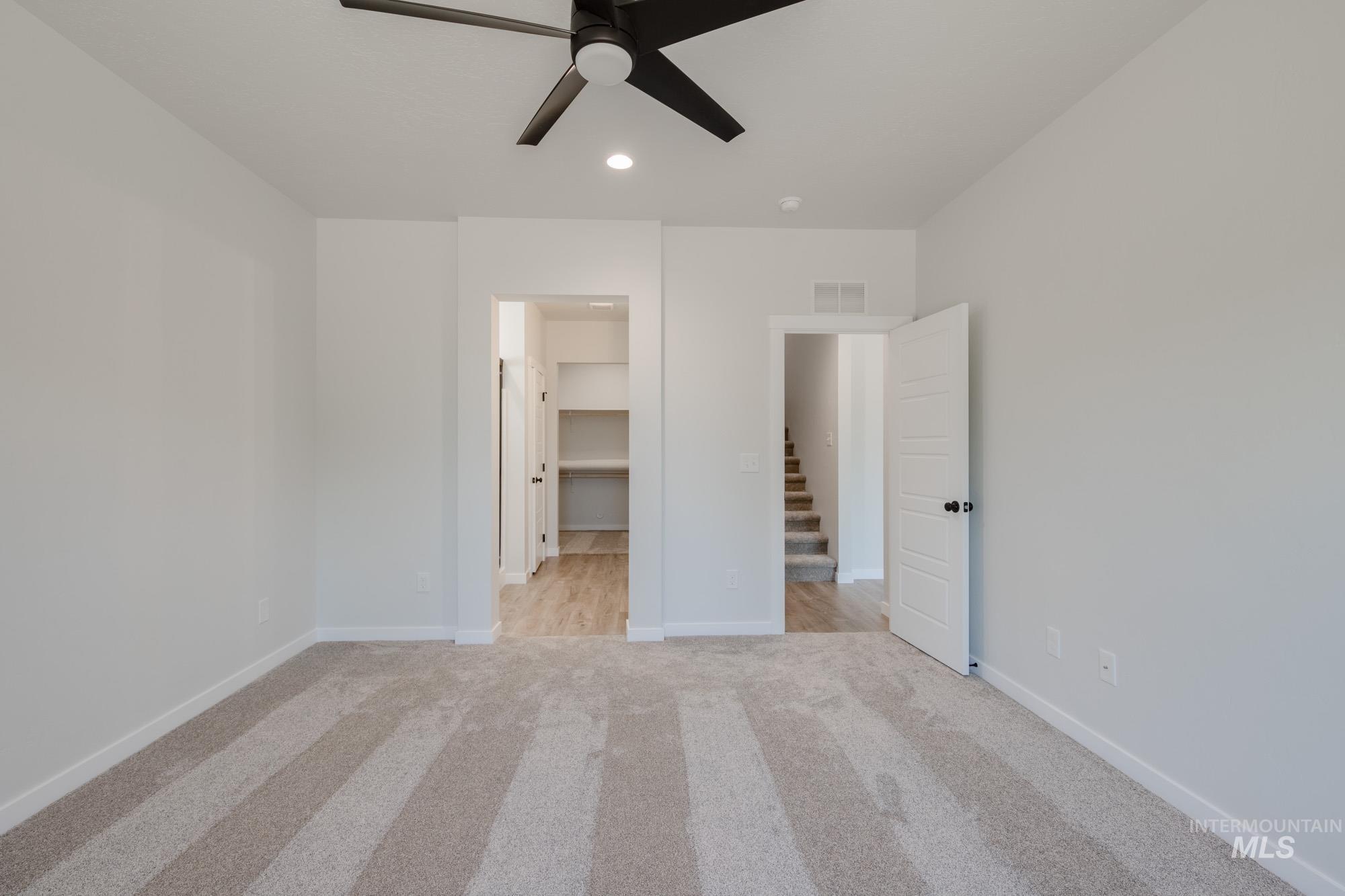 Unfurnished bedroom with light colored carpet, a spacious closet, recessed lighting, and a ceiling fan