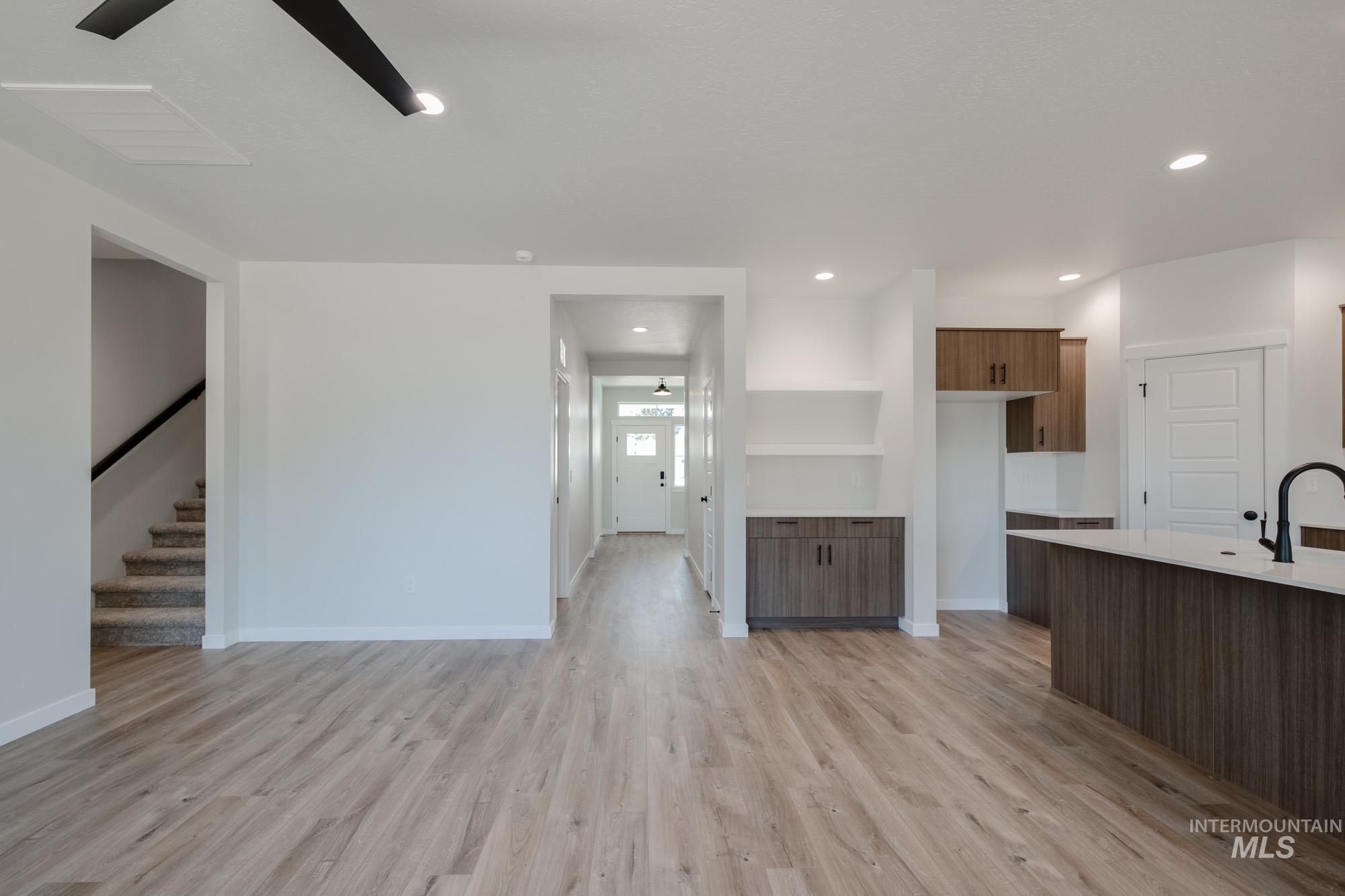 Kitchen featuring light countertops, light wood finished floors, recessed lighting, brown cabinetry, and open floor plan