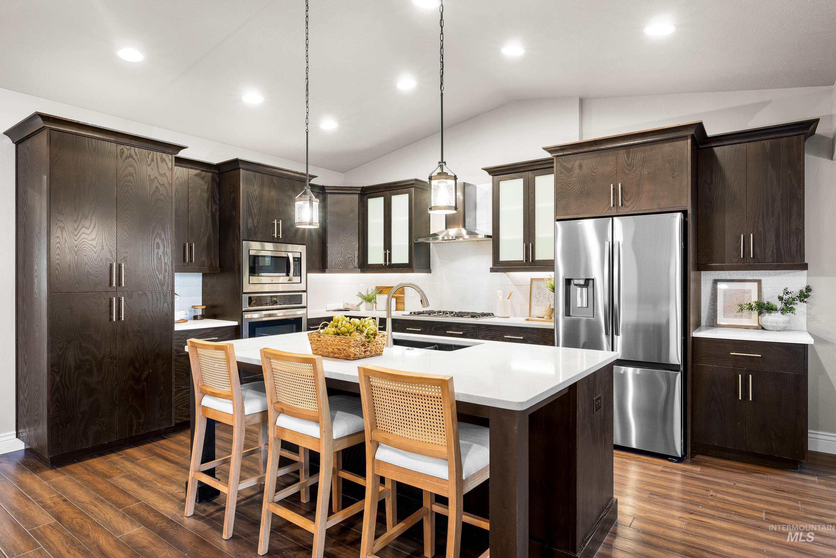 Kitchen with glass insert cabinets, stainless steel appliances, dark brown cabinetry, vaulted ceiling, and a kitchen bar