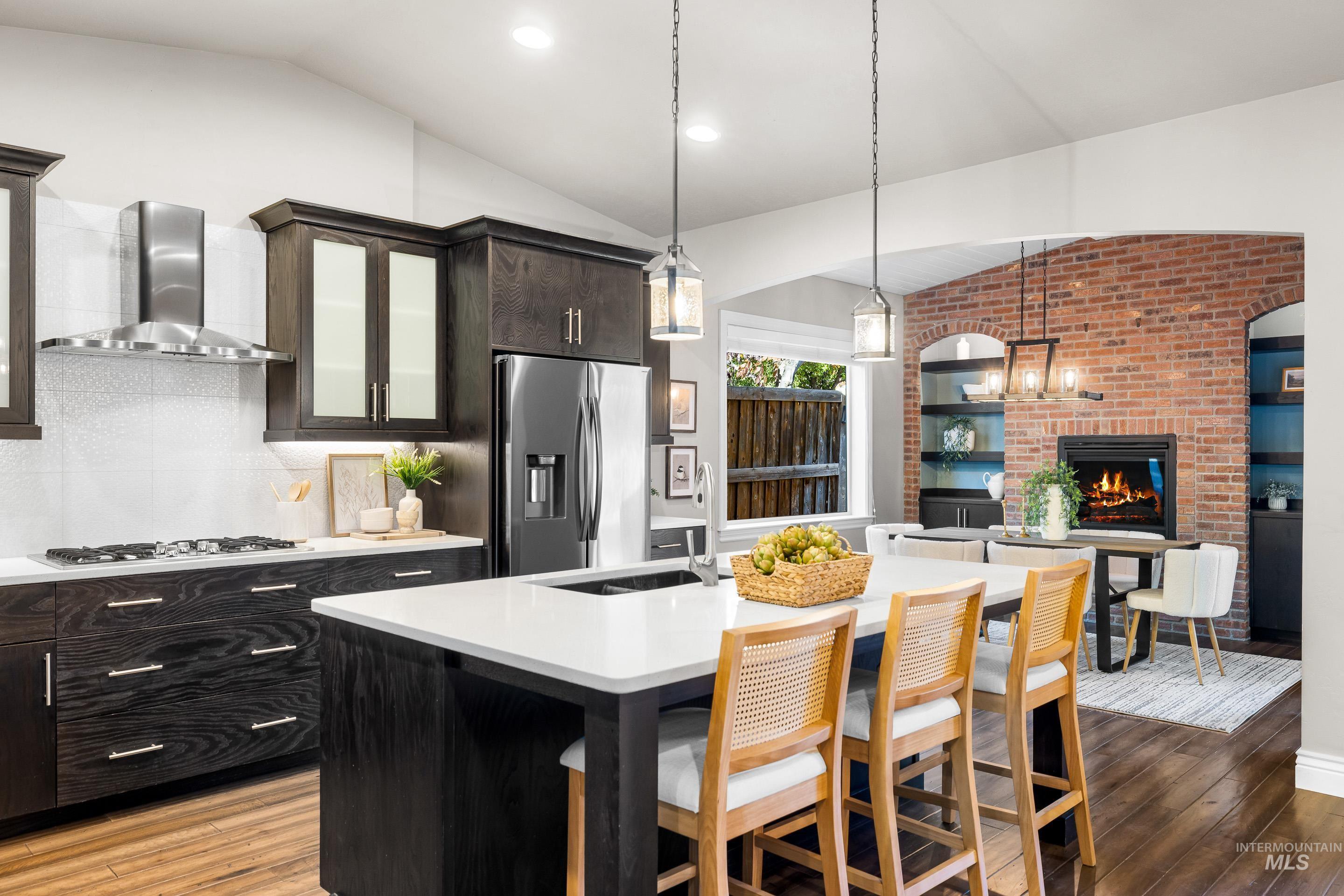 Kitchen featuring lofted ceiling, light wood finished floors, stainless steel appliances, tasteful backsplash, and pendant lighting