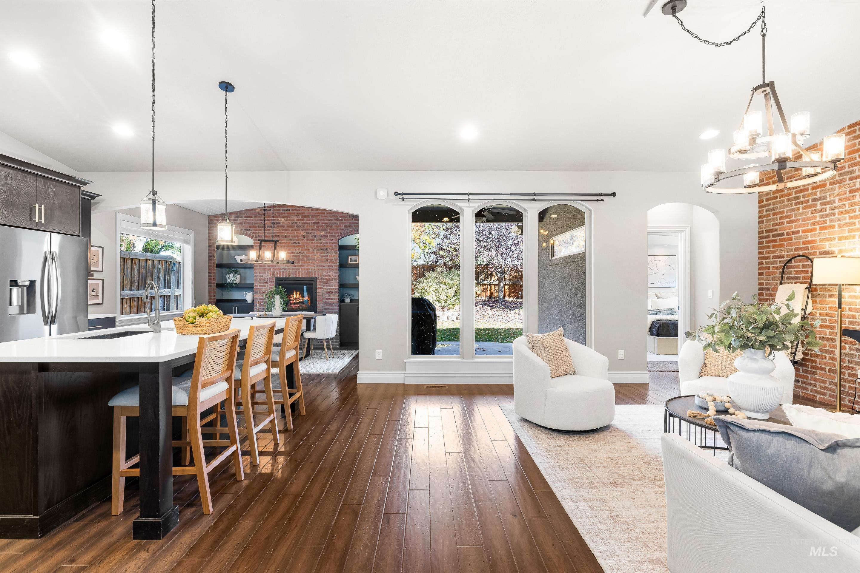 Dining area featuring a fireplace, a chandelier, brick wall, dark wood-style flooring, and arched walkways