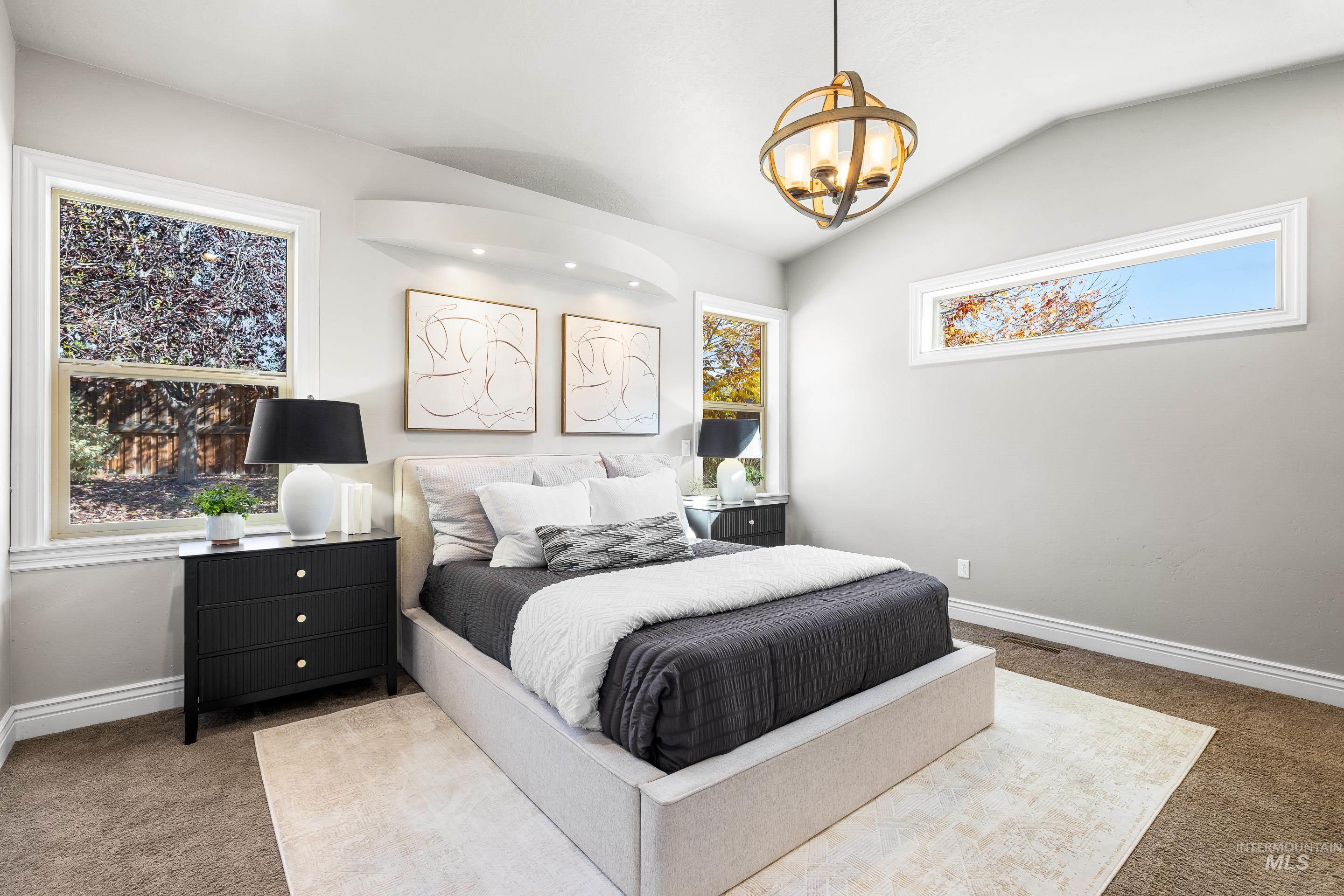 Bedroom featuring carpet flooring, multiple windows, vaulted ceiling, and a chandelier