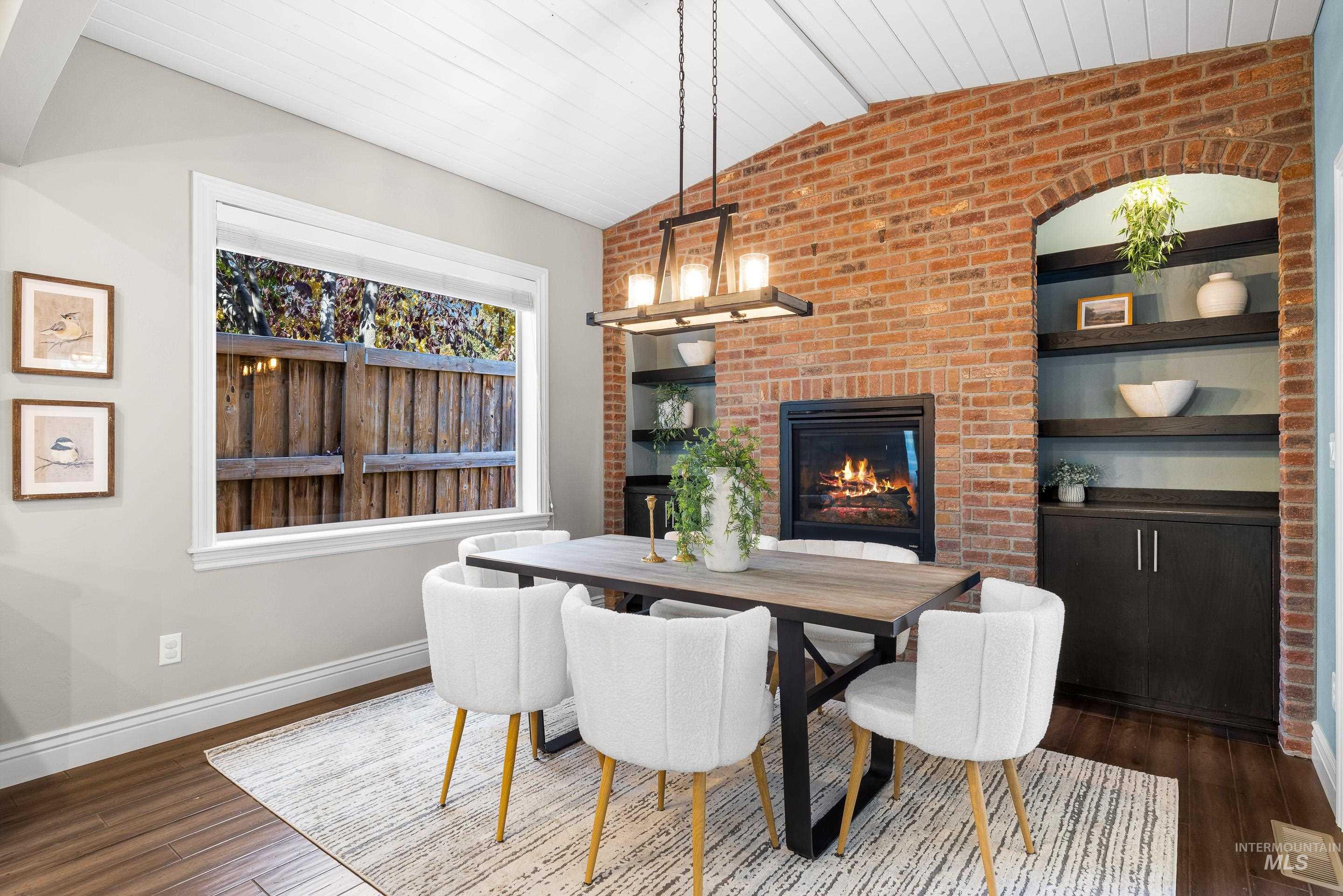 Dining area featuring brick wall, lofted ceiling, a fireplace, wood finished floors, and wooden ceiling