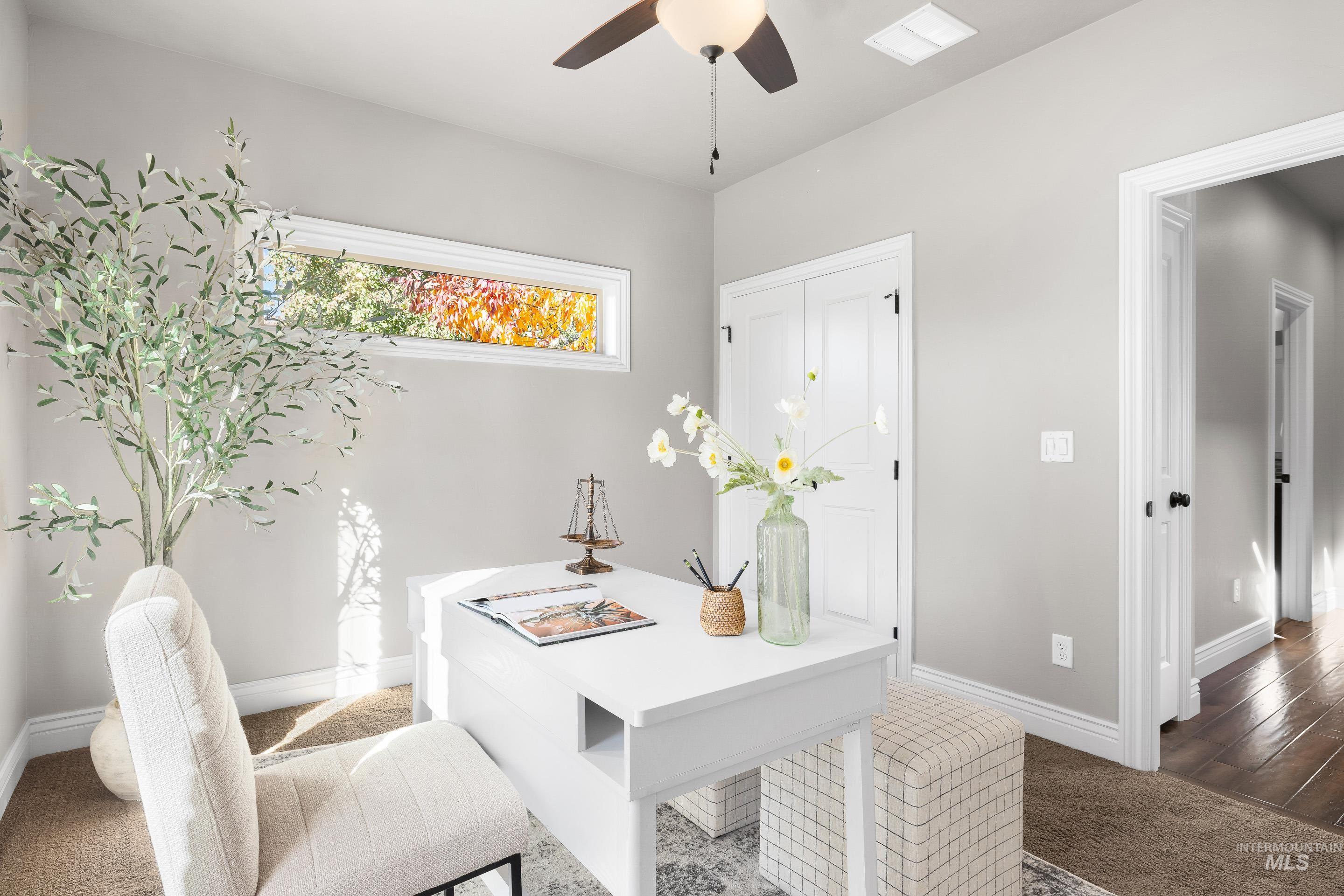 Carpeted office featuring baseboards and a ceiling fan
