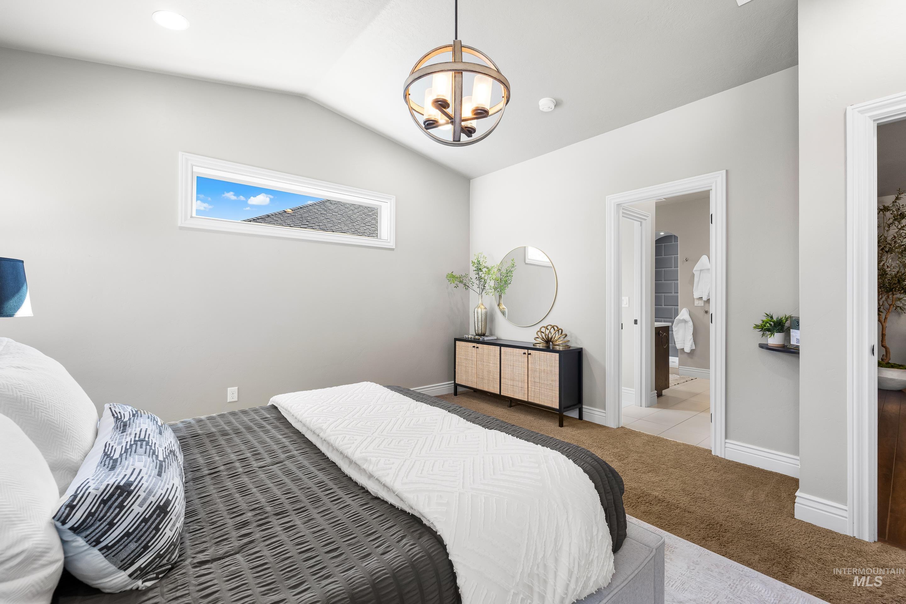 Bedroom with vaulted ceiling, a chandelier, carpet flooring, and connected bathroom