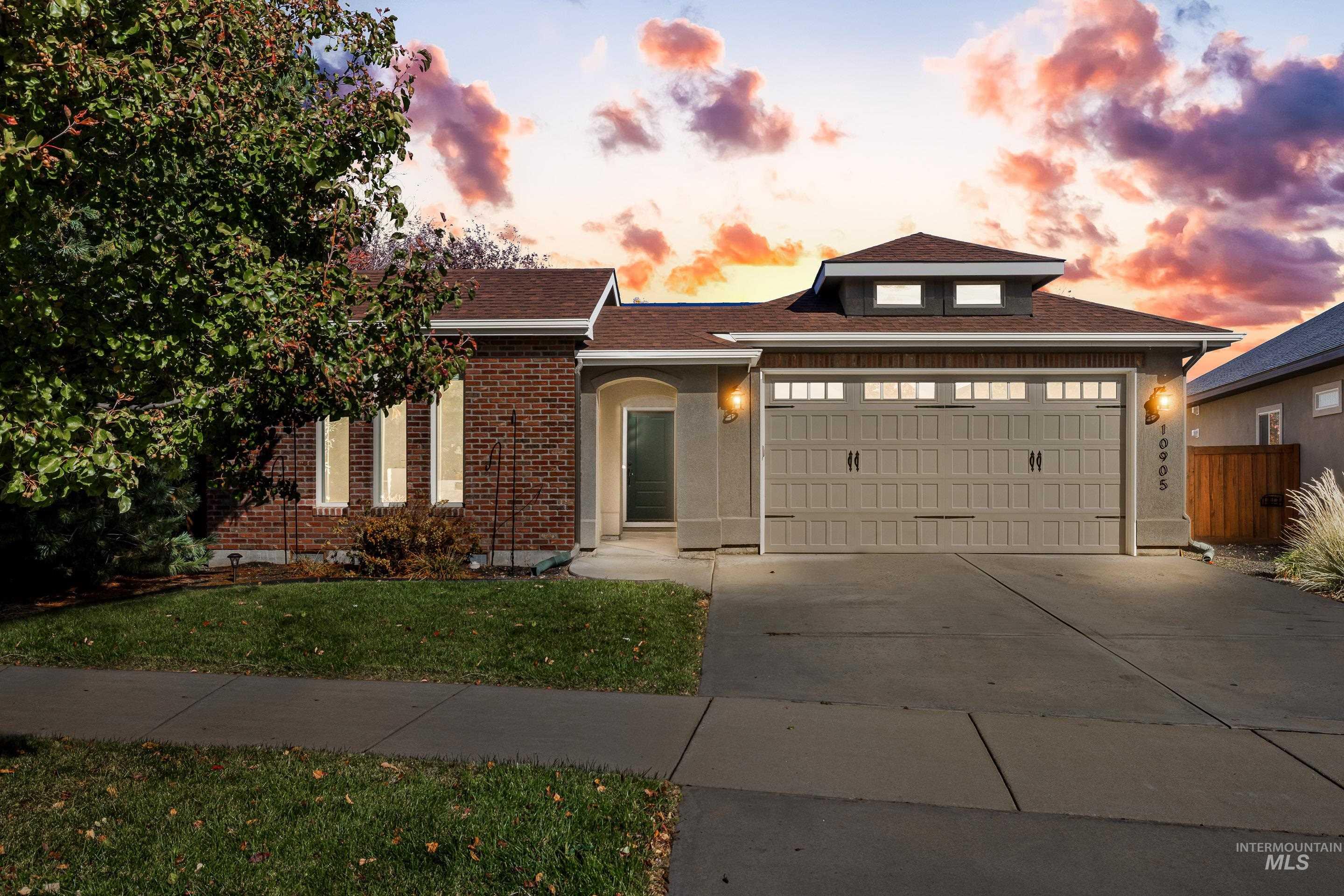 View of front of house featuring driveway, a garage, brick siding, a yard, and roof with shingles