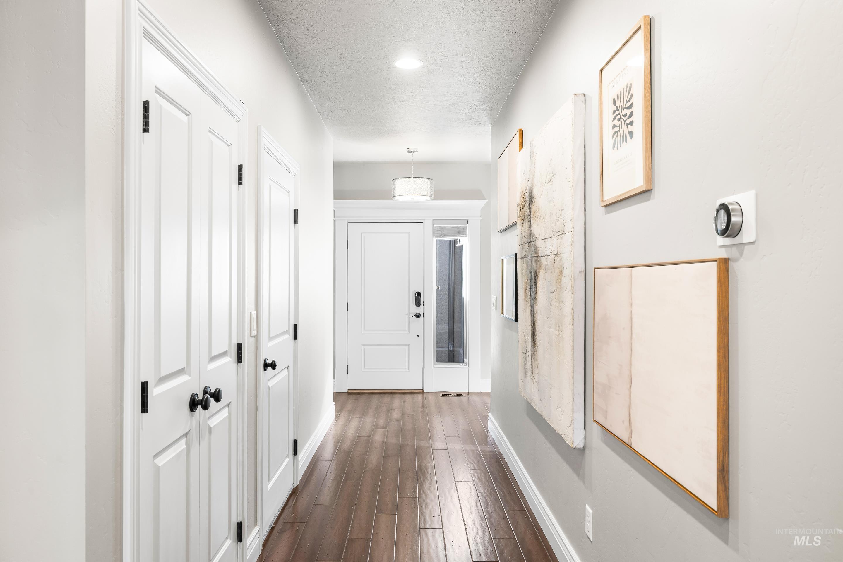 Corridor with dark wood-type flooring and a textured ceiling