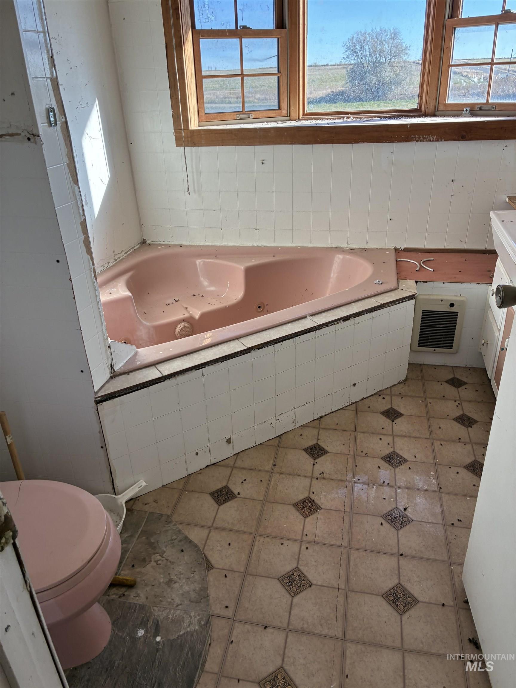 Bathroom with a jetted tub, vanity, light tile patterned flooring, and heating unit