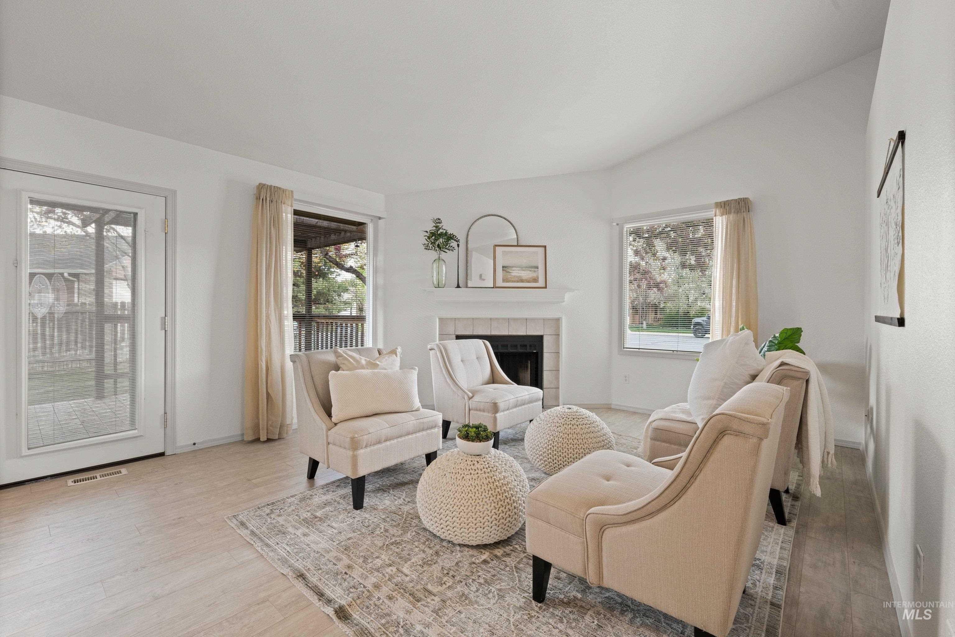 Living area featuring light wood-style flooring, a tile fireplace, and vaulted ceiling