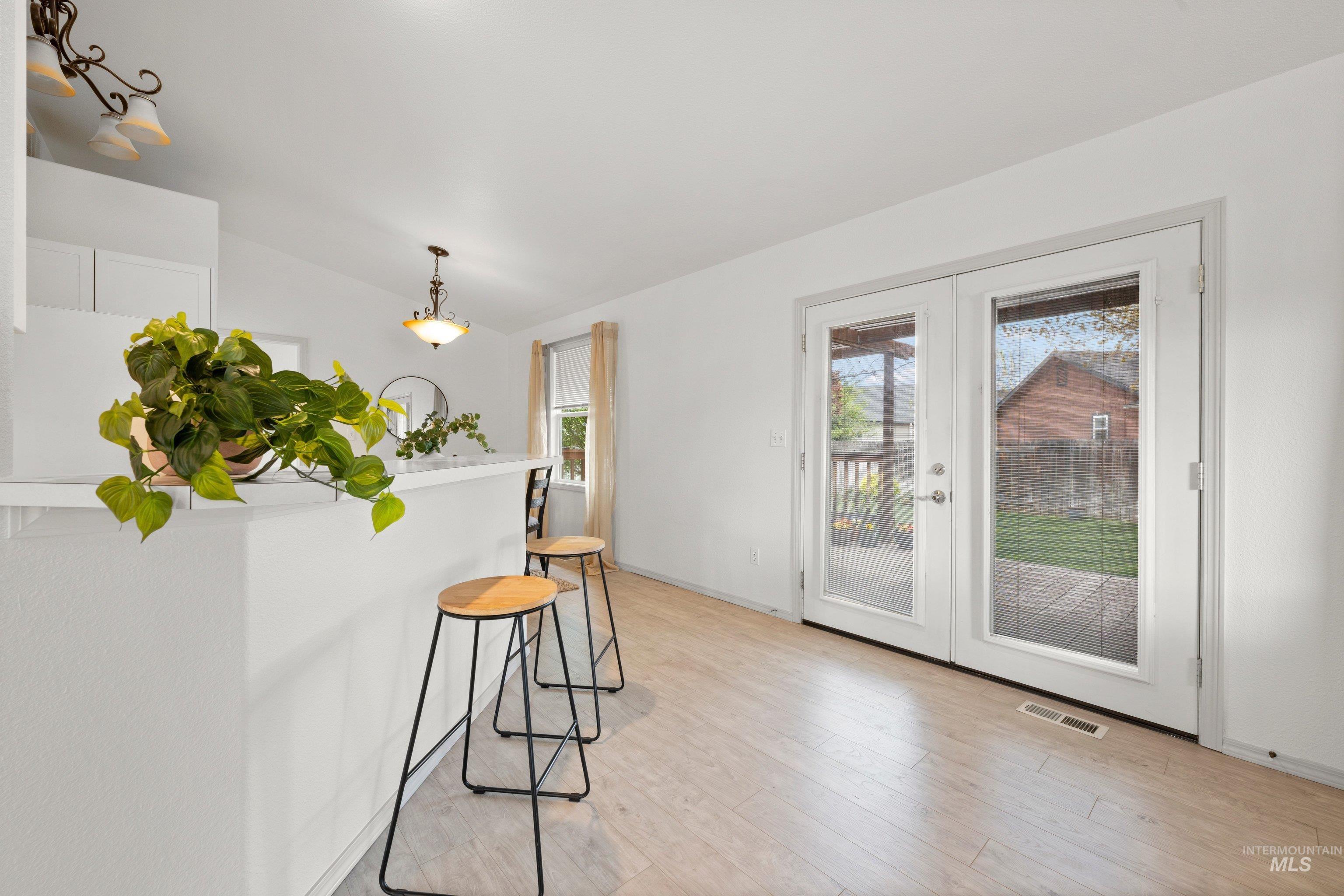 Dining area with french doors, light wood finished floors, and vaulted ceiling