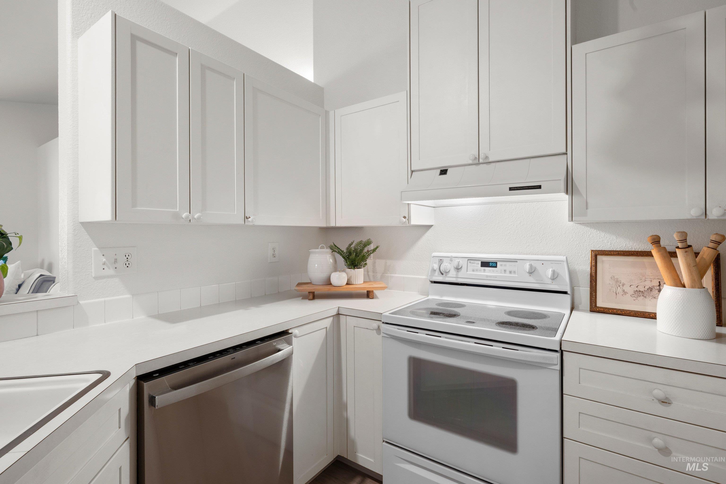 Kitchen with white electric range oven, light countertops, and white cabinets