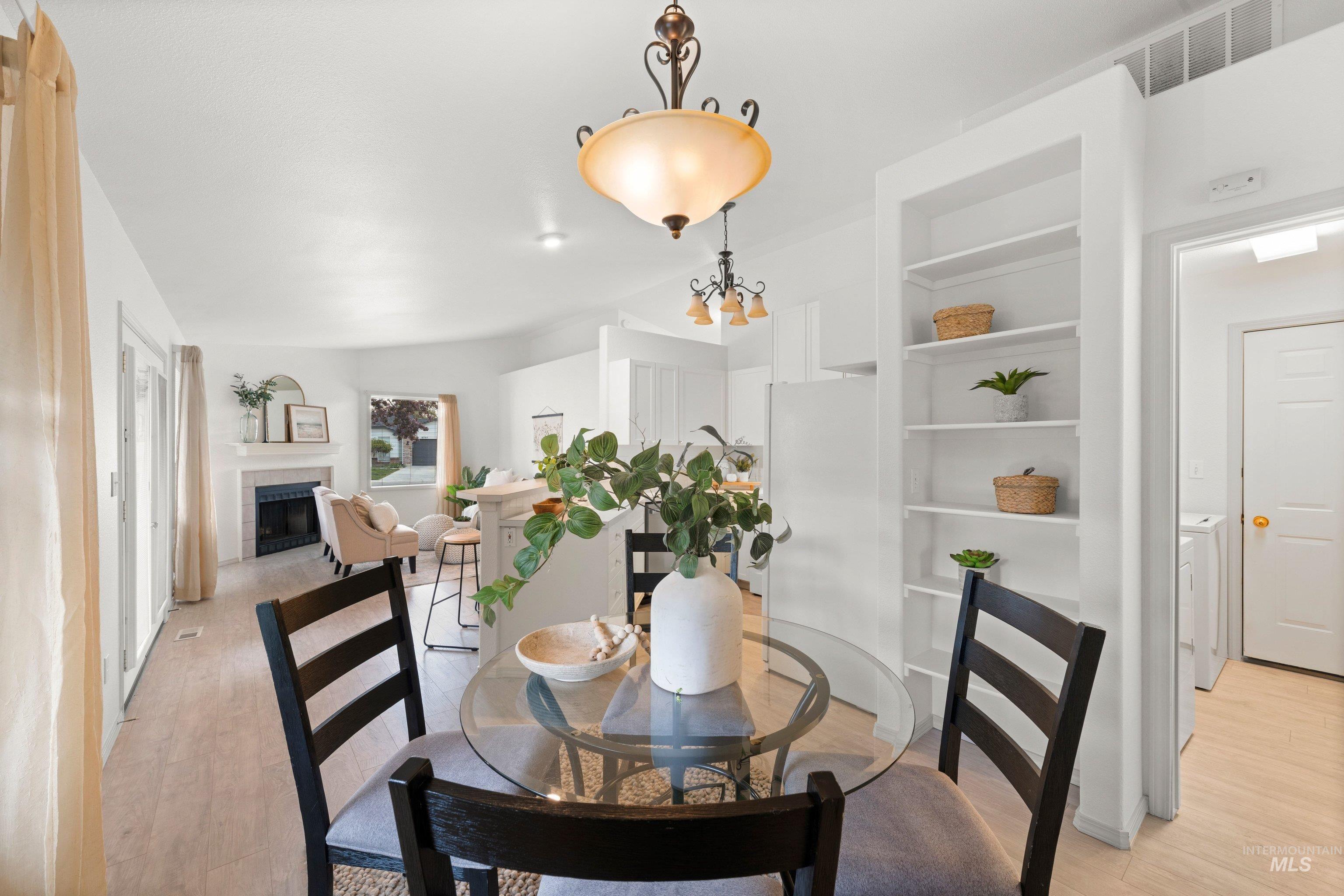 Dining area with a fireplace, light wood-style floors, and a chandelier
