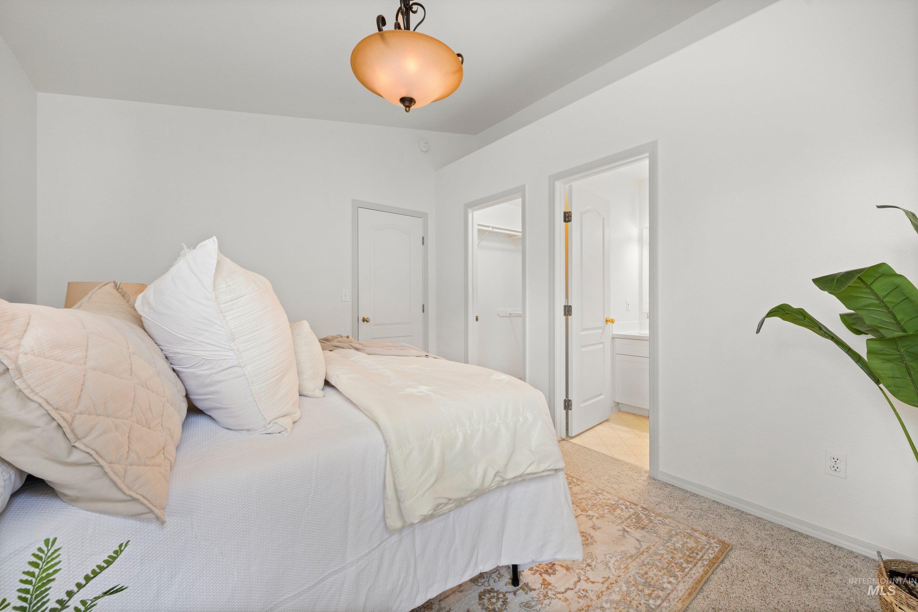 Bedroom featuring ensuite bathroom, a walk in closet, and light carpet