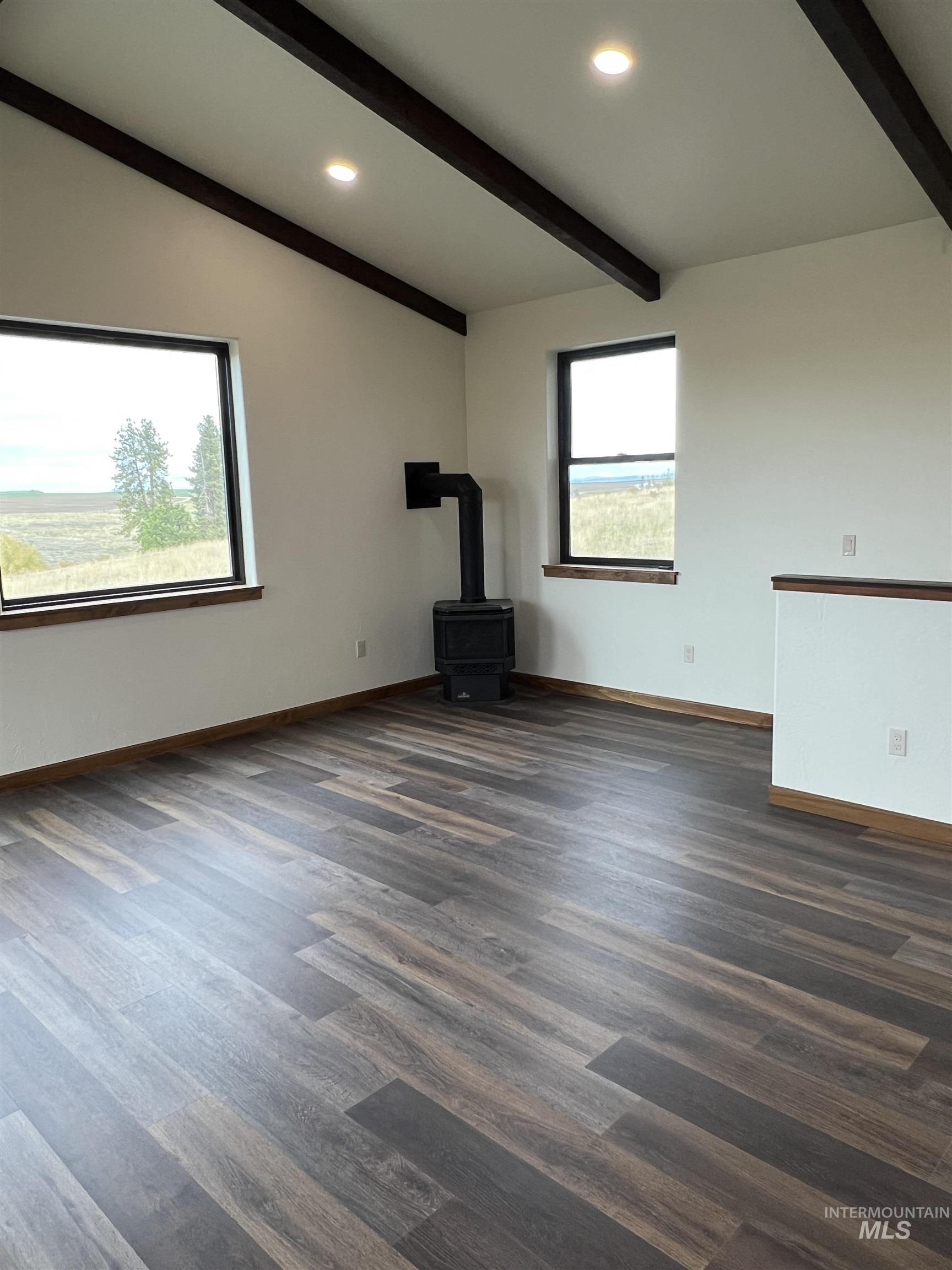 Unfurnished living room featuring a wood stove, recessed lighting, beamed ceiling, and dark wood-style floors