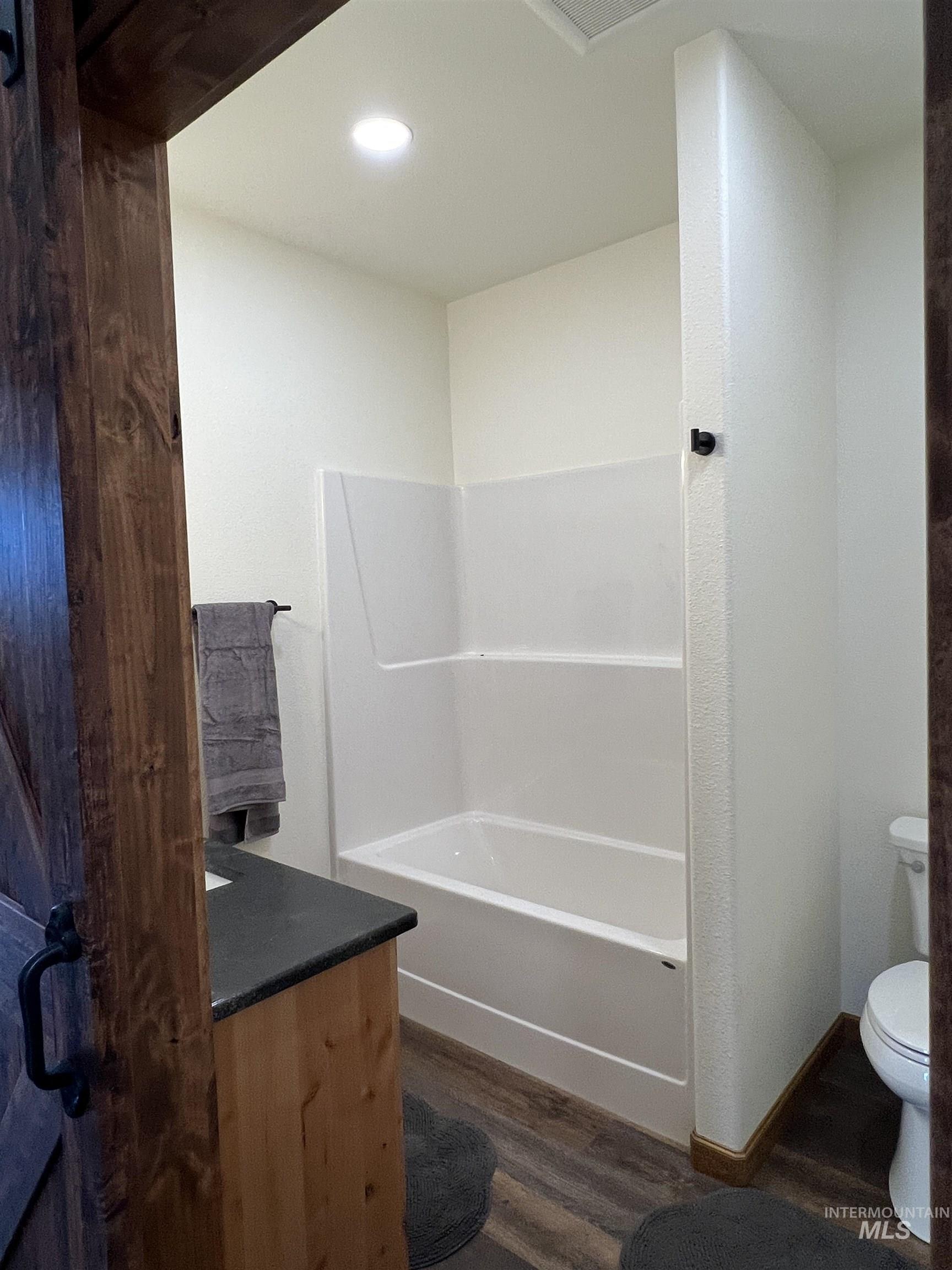 Full bath featuring dark wood finished floors, vanity, shower / tub combination, and recessed lighting