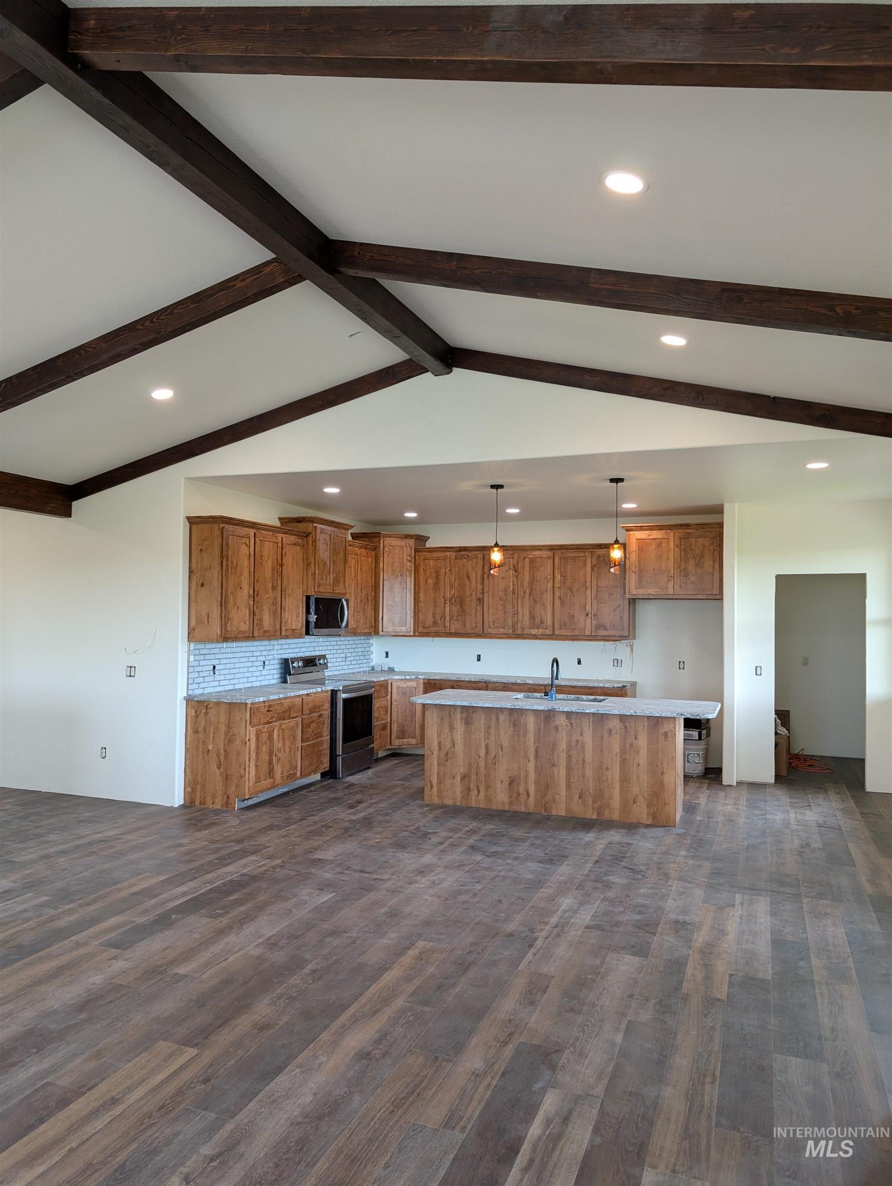 Kitchen with recessed lighting, brown cabinetry, hanging light fixtures, appliances with stainless steel finishes, and a center island with sink