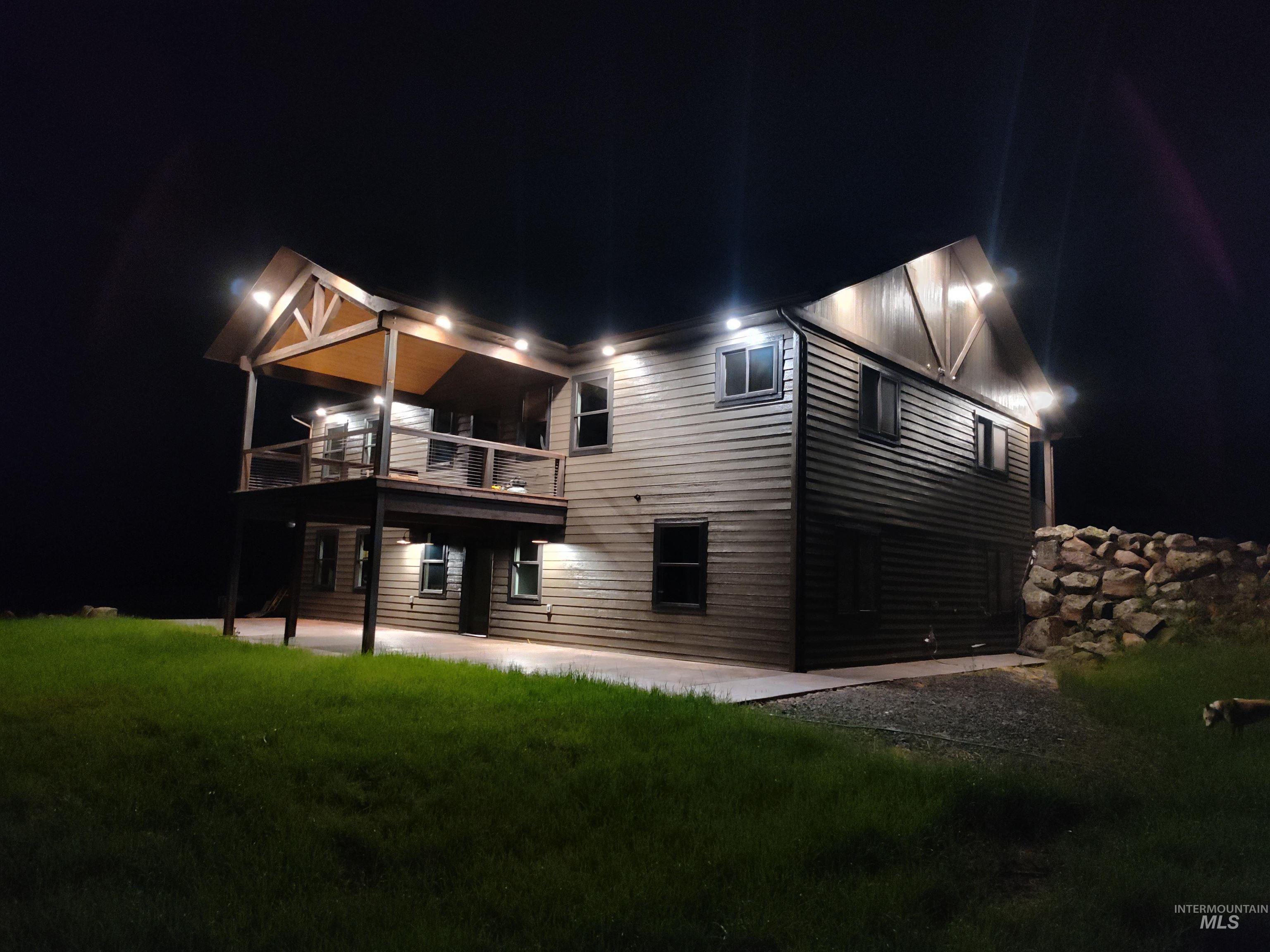 Back of house at twilight with a patio area and a lawn