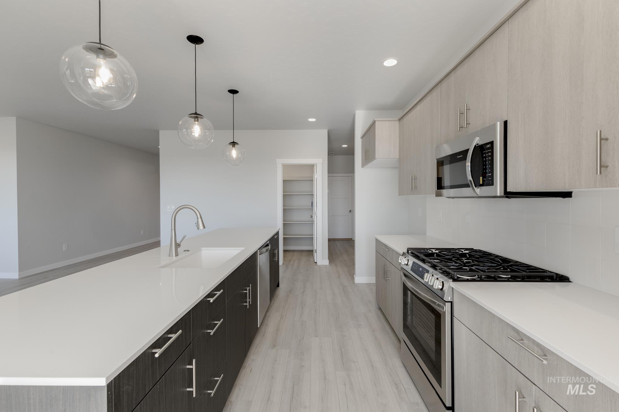 Kitchen with appliances with stainless steel finishes, modern cabinets, pendant lighting, an island with sink, and backsplash
