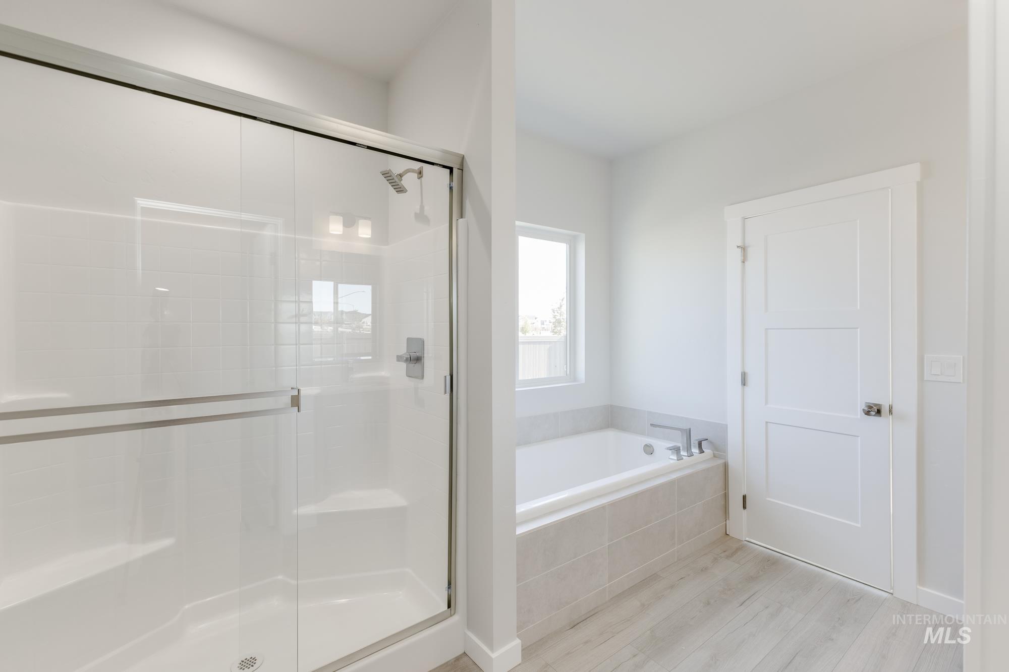Bathroom with light wood finished floors, a shower stall, and a bath