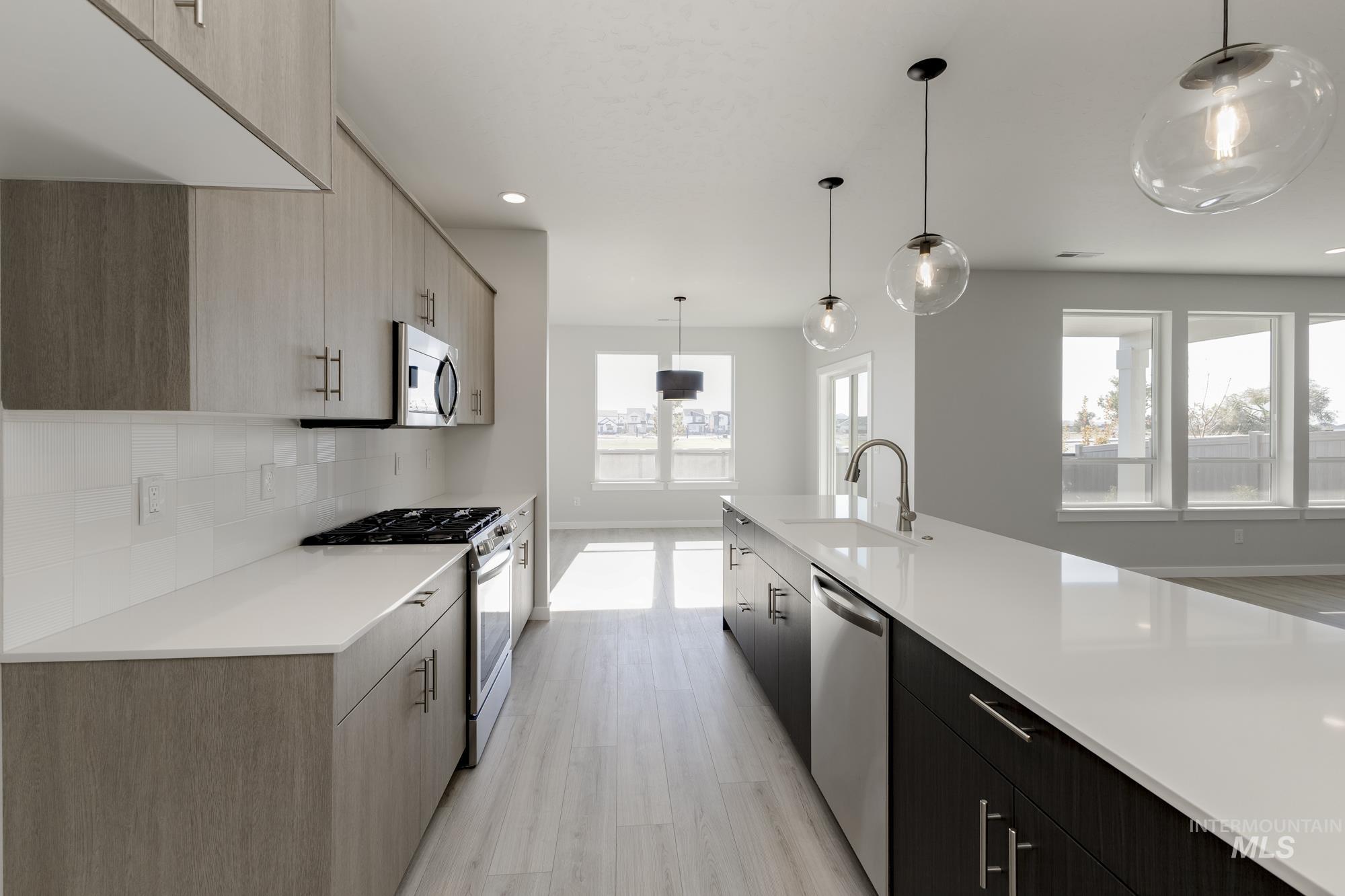 Kitchen with appliances with stainless steel finishes, hanging light fixtures, modern cabinets, tasteful backsplash, and recessed lighting