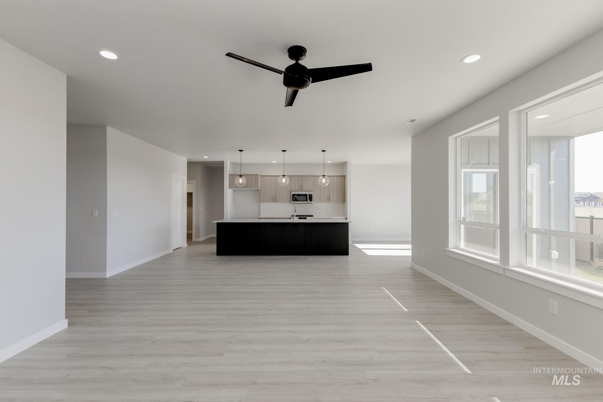 Unfurnished living room featuring a ceiling fan, light wood finished floors, and recessed lighting