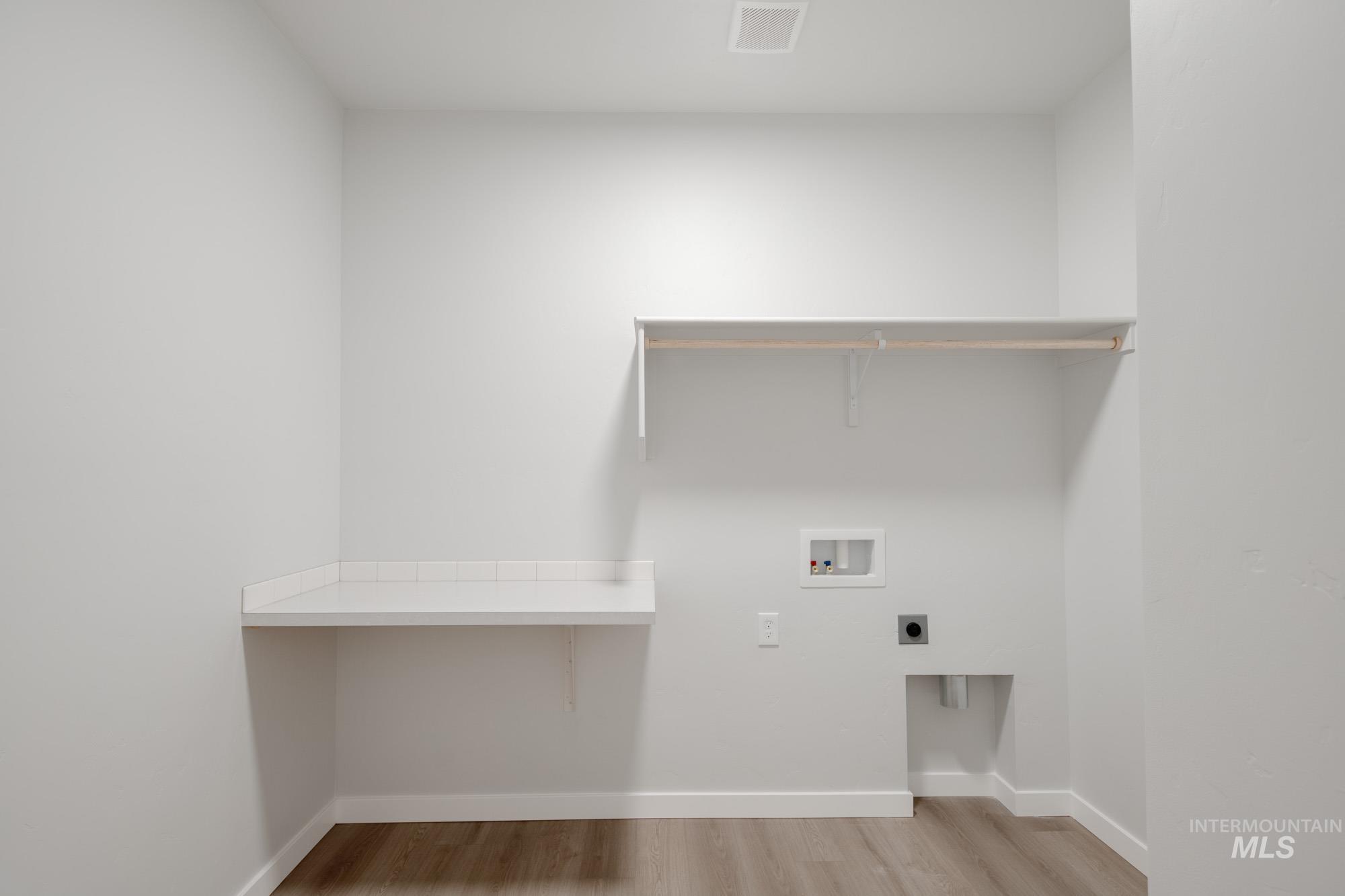 Laundry area with light wood-type flooring, washer hookup, and hookup for an electric dryer