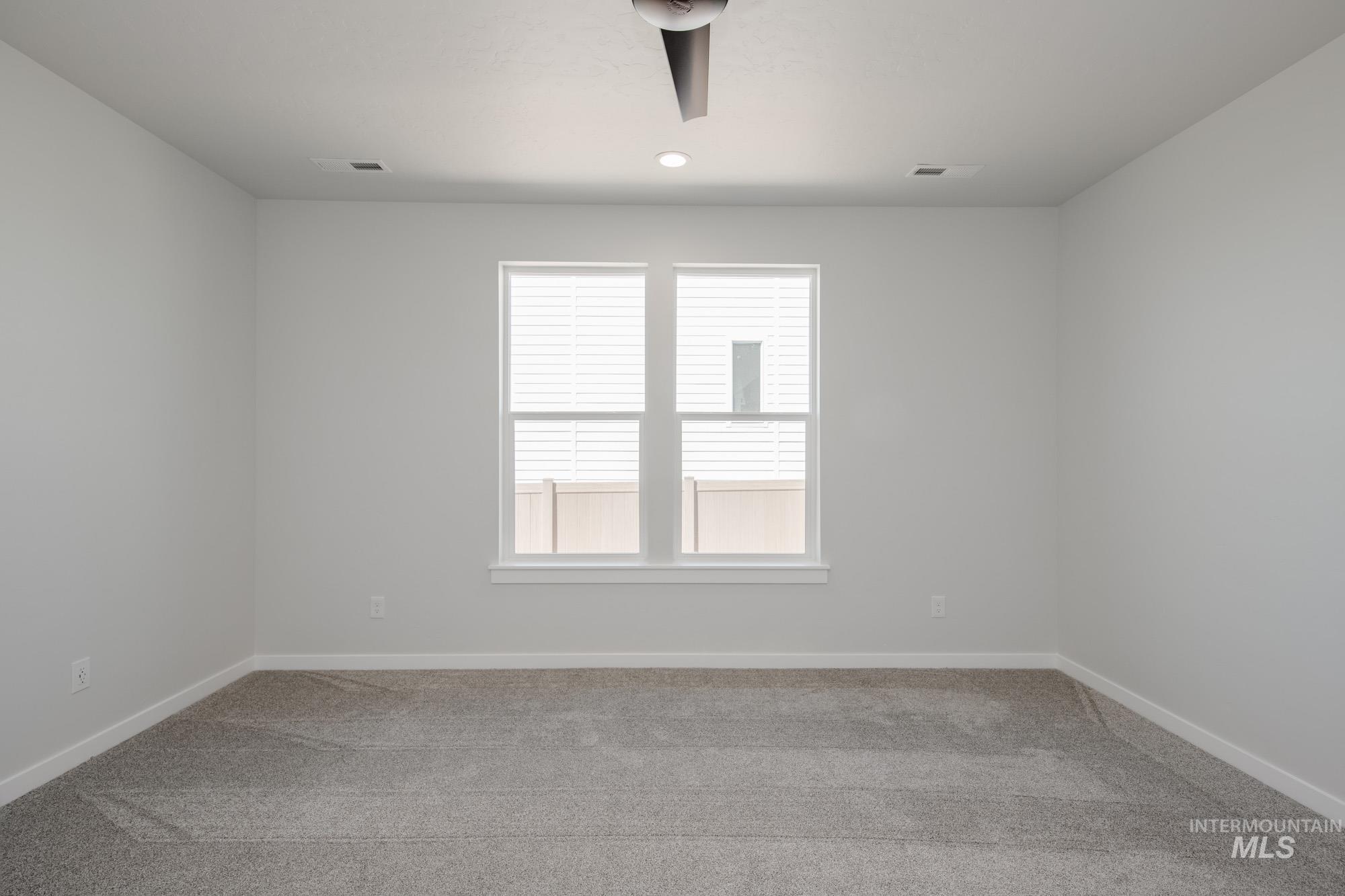 Empty room with light carpet and recessed lighting