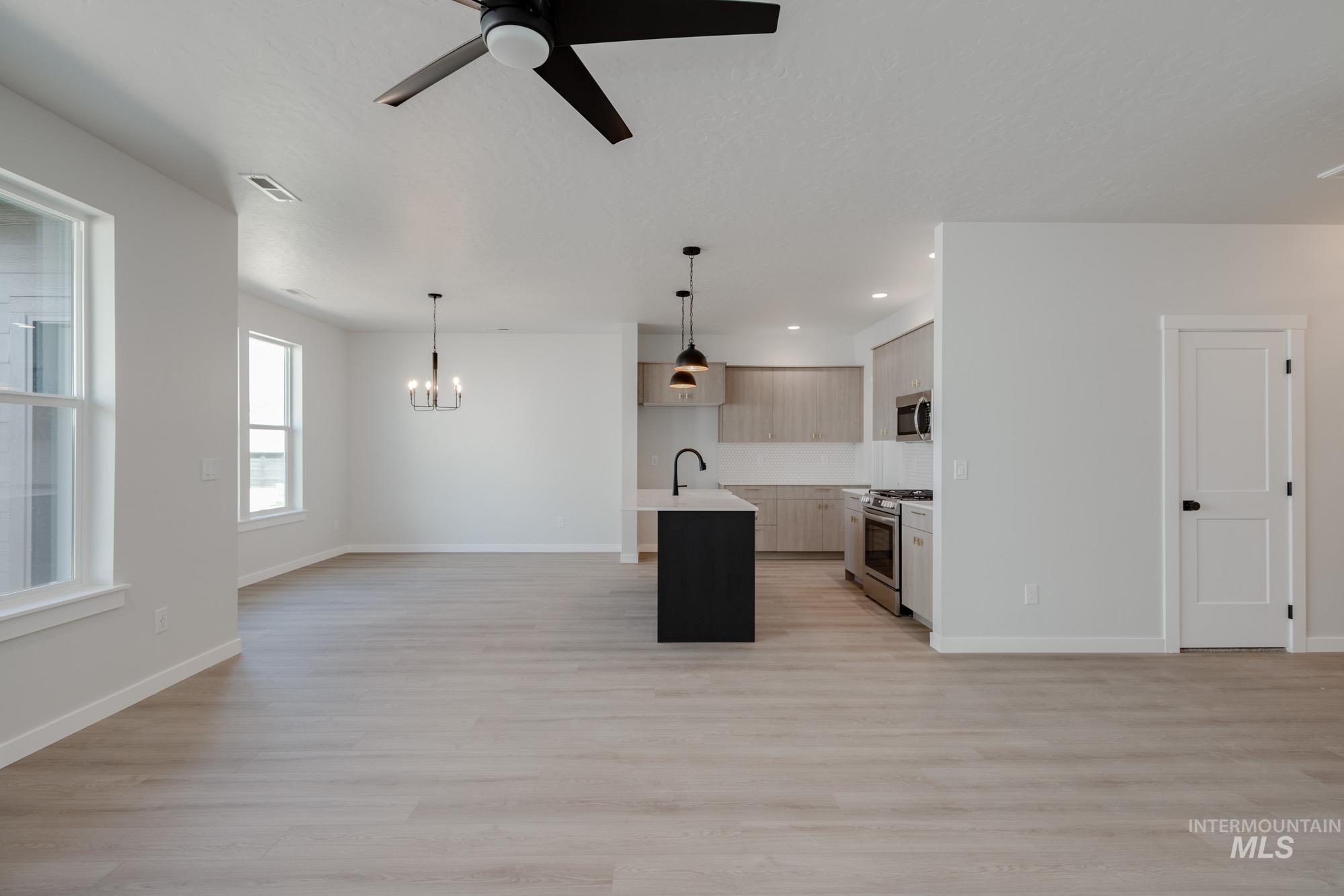 Kitchen with open floor plan, a center island with sink, light wood-style flooring, stainless steel appliances, and recessed lighting