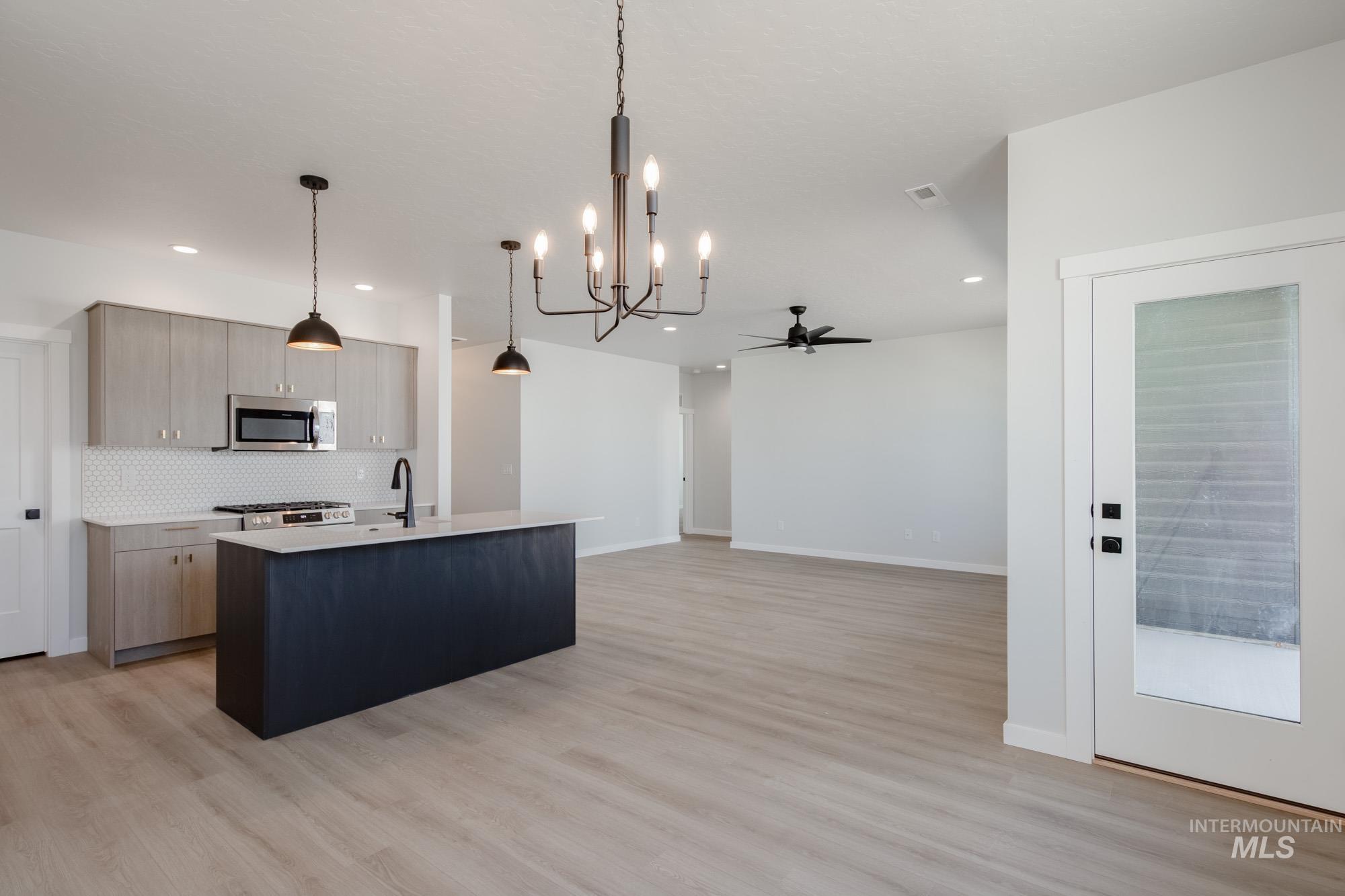 Kitchen with a chandelier, a kitchen island with sink, decorative light fixtures, ceiling fan, and backsplash