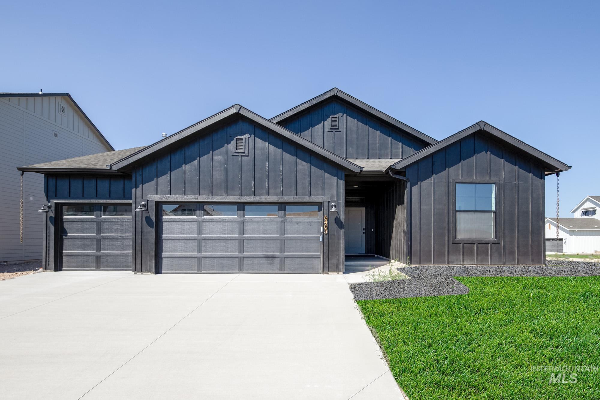 View of front facade with board and batten siding, an attached garage, concrete driveway, a front yard, and a shingled roof
