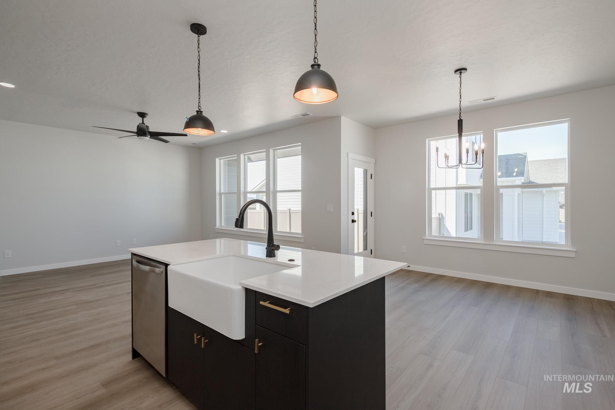 Kitchen featuring dark cabinetry, pendant lighting, a chandelier, and light wood-type flooring