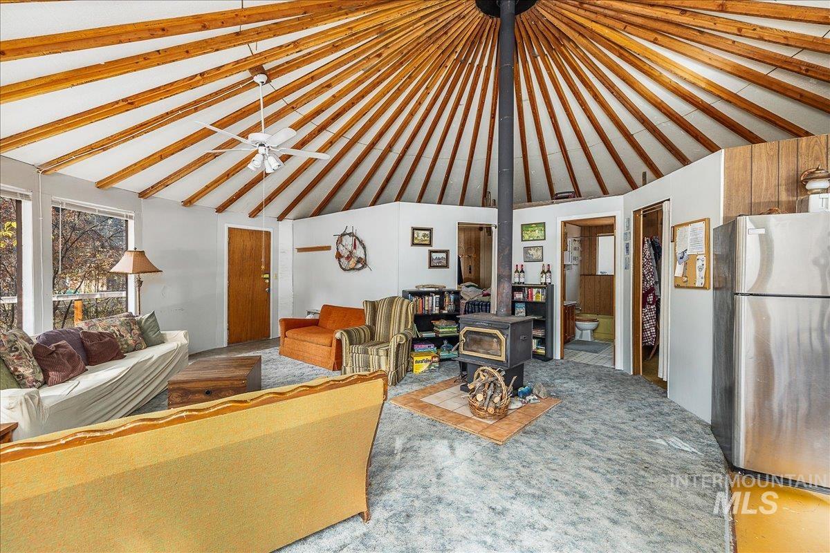 Carpeted living area featuring a wood stove and high vaulted ceiling