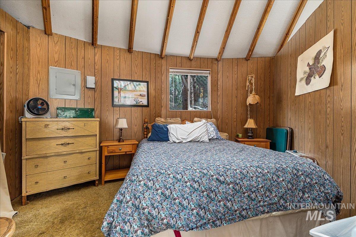 Bedroom featuring wood walls, carpet flooring, and electric panel