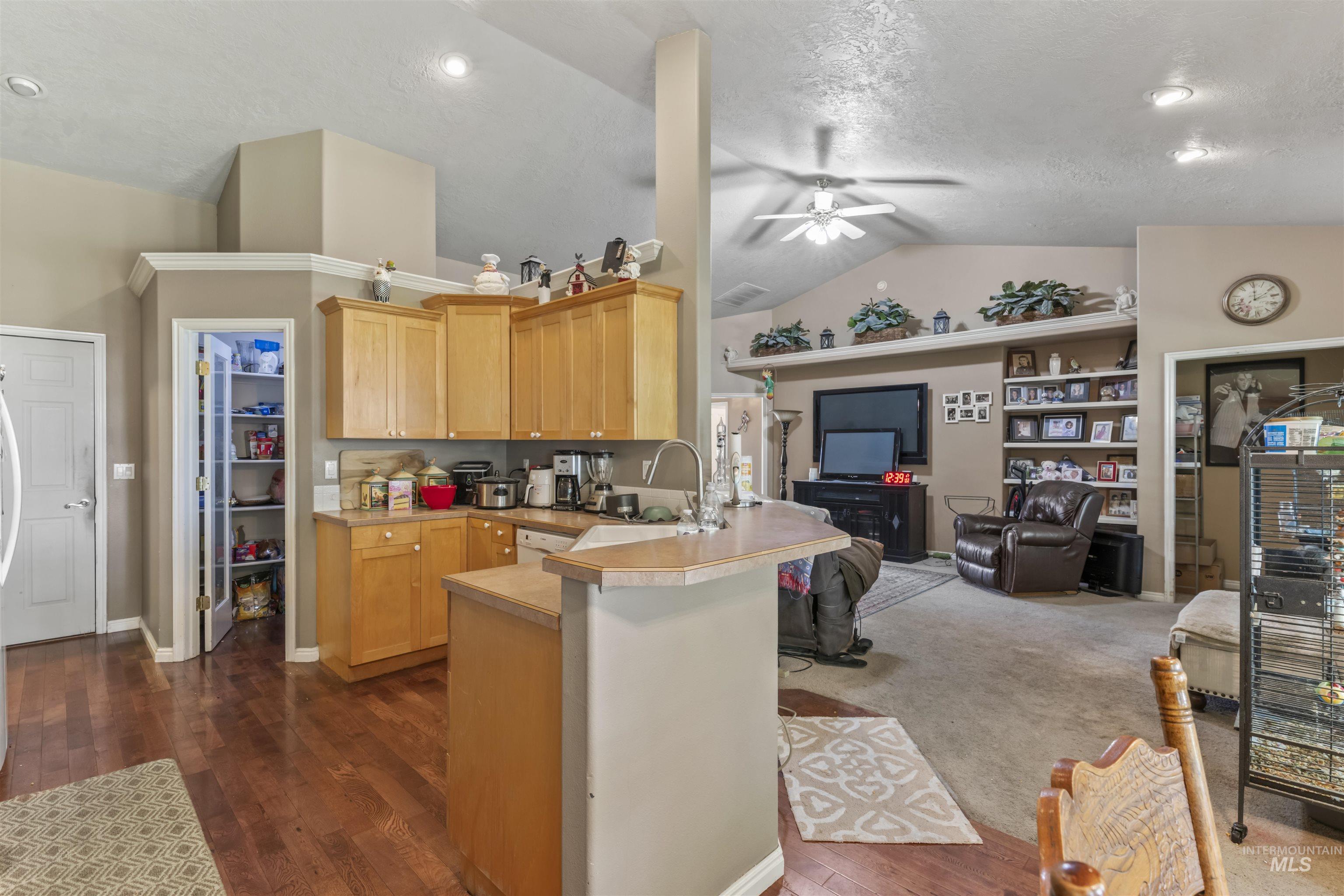 Kitchen featuring a peninsula, ceiling fan, lofted ceiling, open floor plan, and light countertops