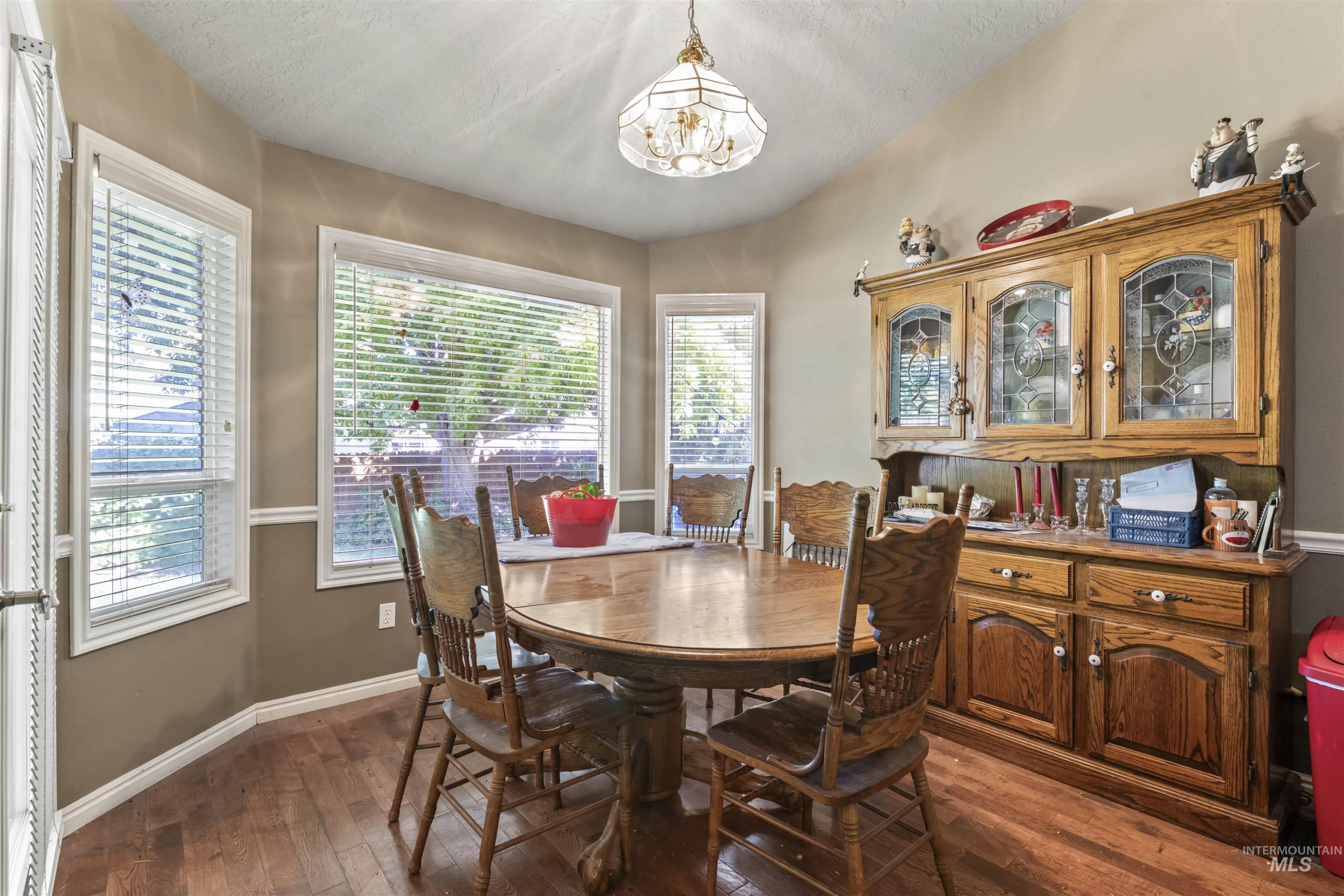 Dining space with dark wood-type flooring, a chandelier, and a textured ceiling