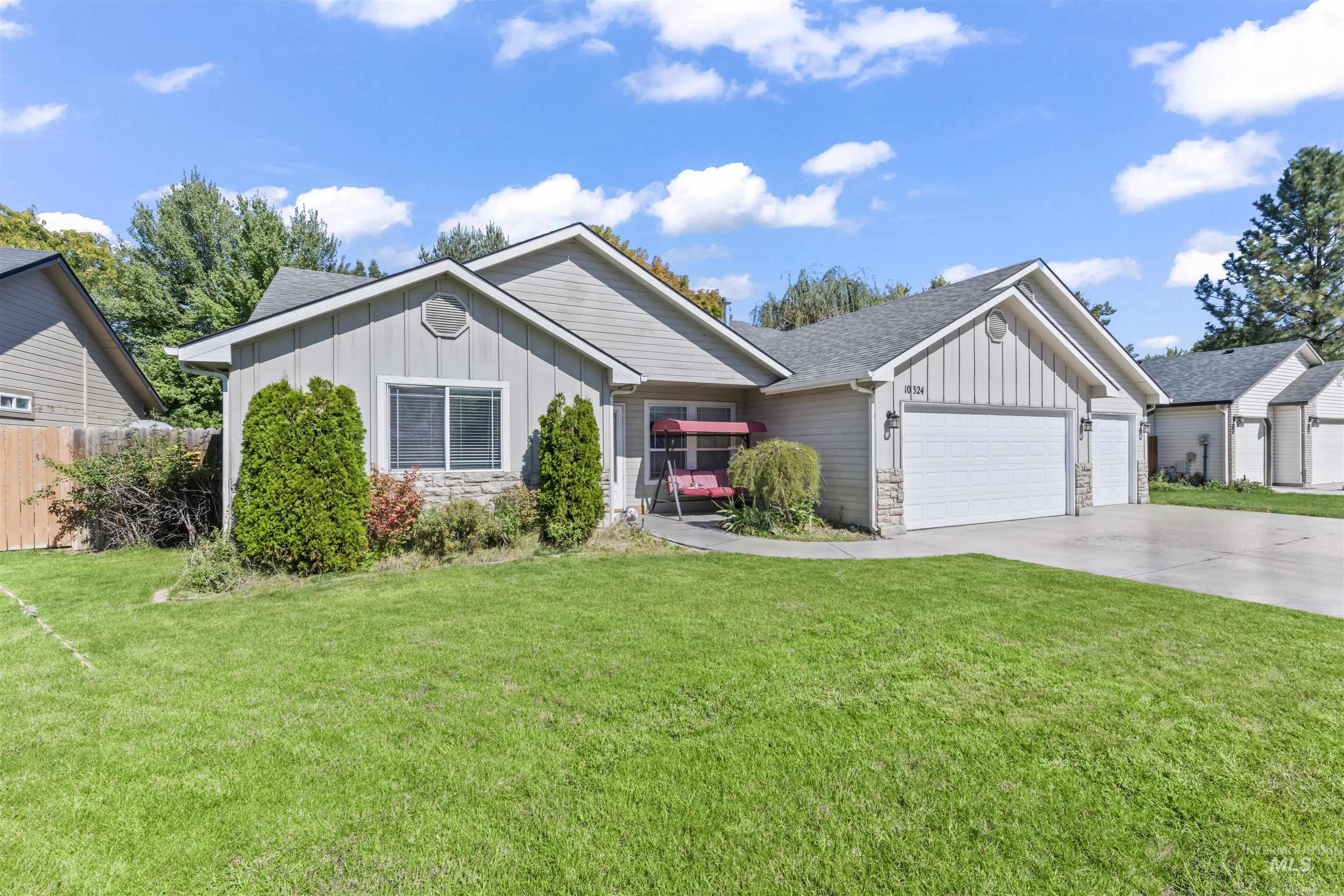 Single story home featuring board and batten siding, stone siding, a front yard, and driveway