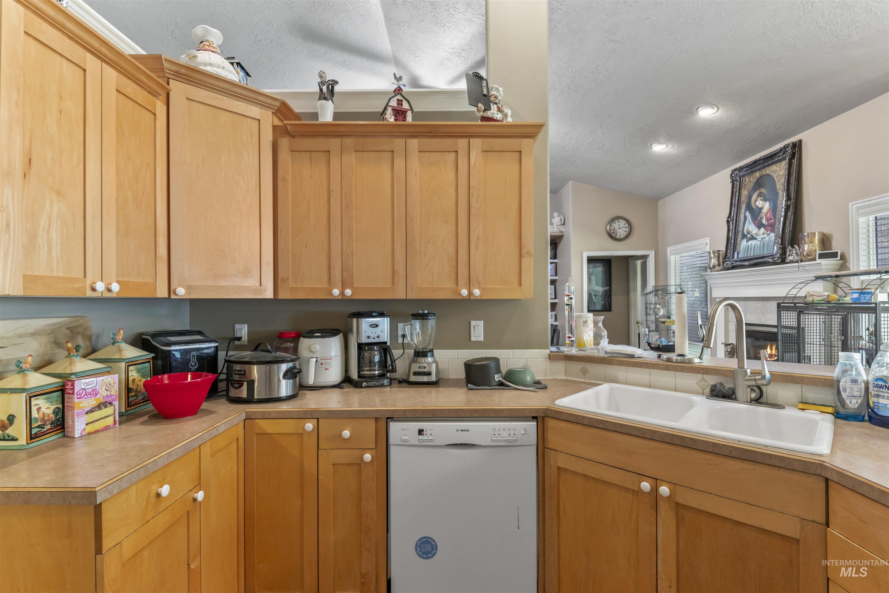 Kitchen featuring white dishwasher, light countertops, and a textured ceiling