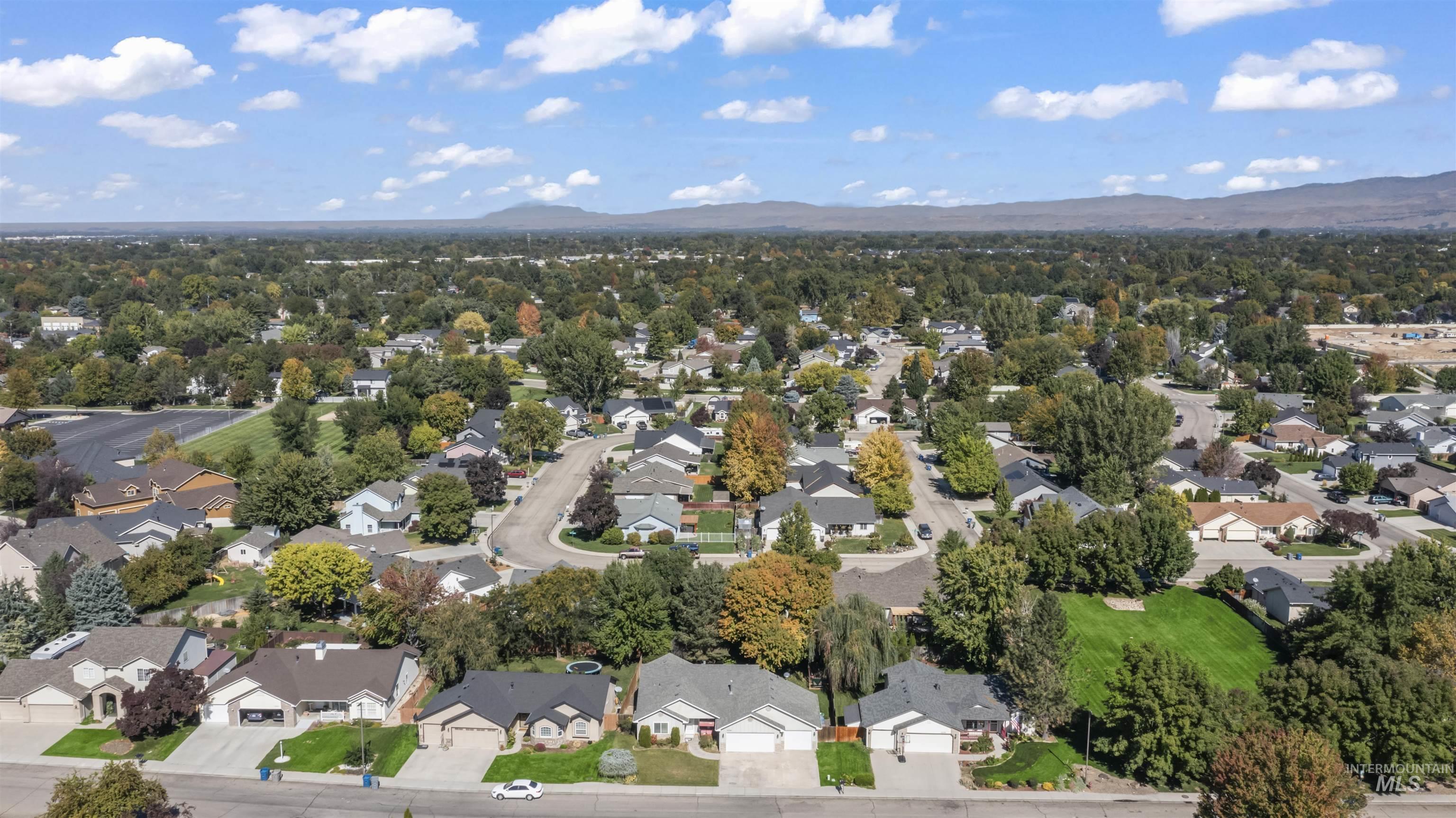 Aerial view of property and surrounding area featuring a mountain backdrop and nearby suburban area