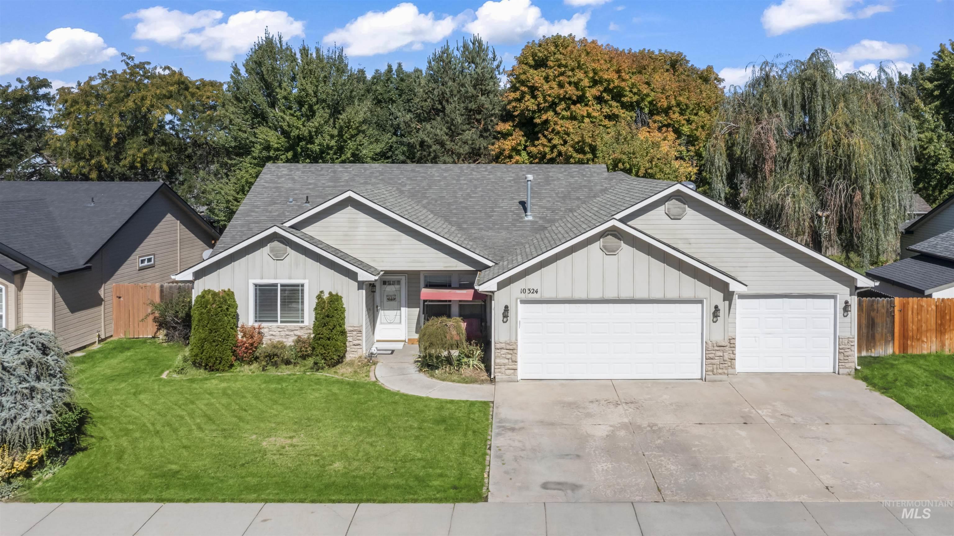 Craftsman-style house featuring board and batten siding, stone siding, a shingled roof, an attached garage, and driveway