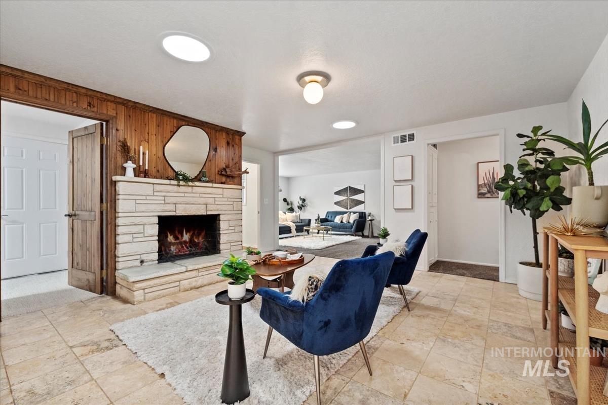 Living area with a fireplace, wooden walls, and stone tile floors