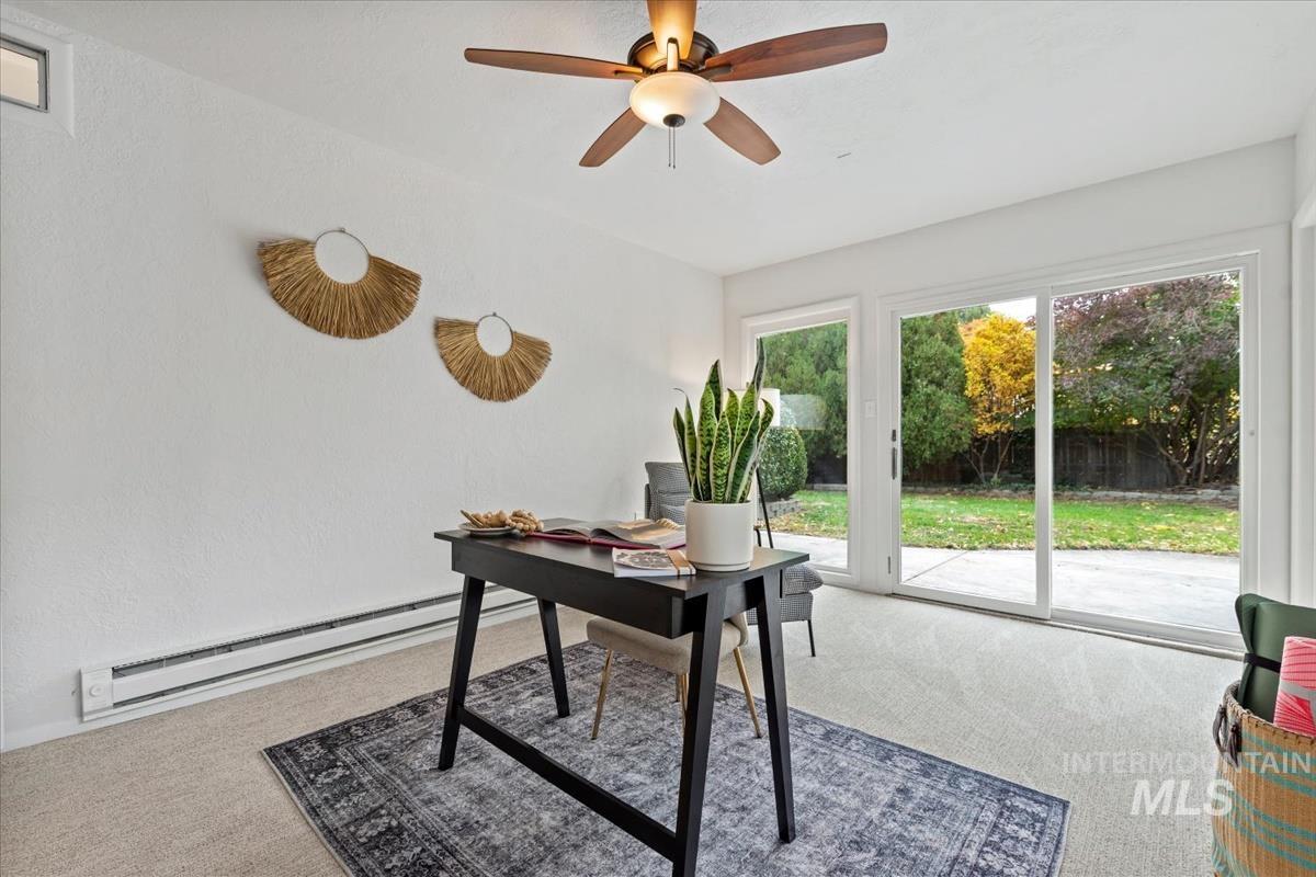 Home office featuring light colored carpet, baseboard heating, and a ceiling fan