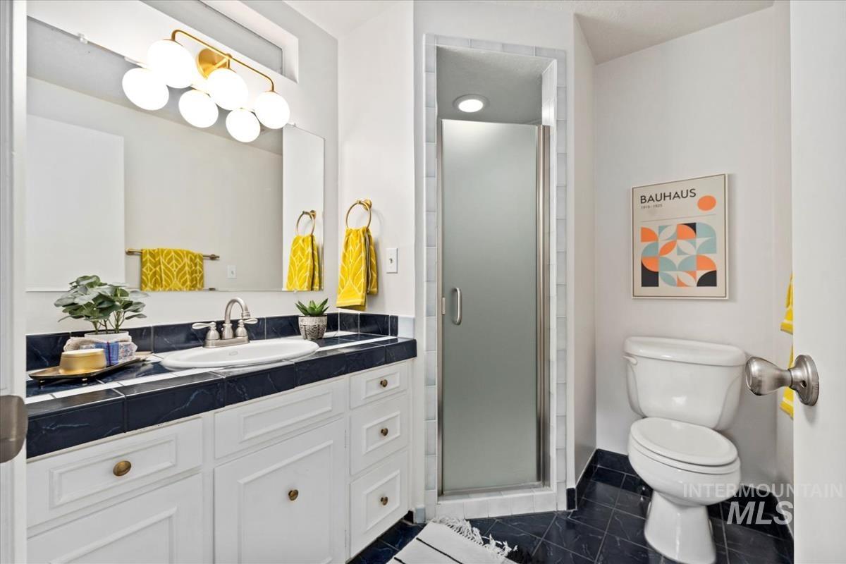 Bathroom with vanity, a shower stall, and dark tile patterned flooring