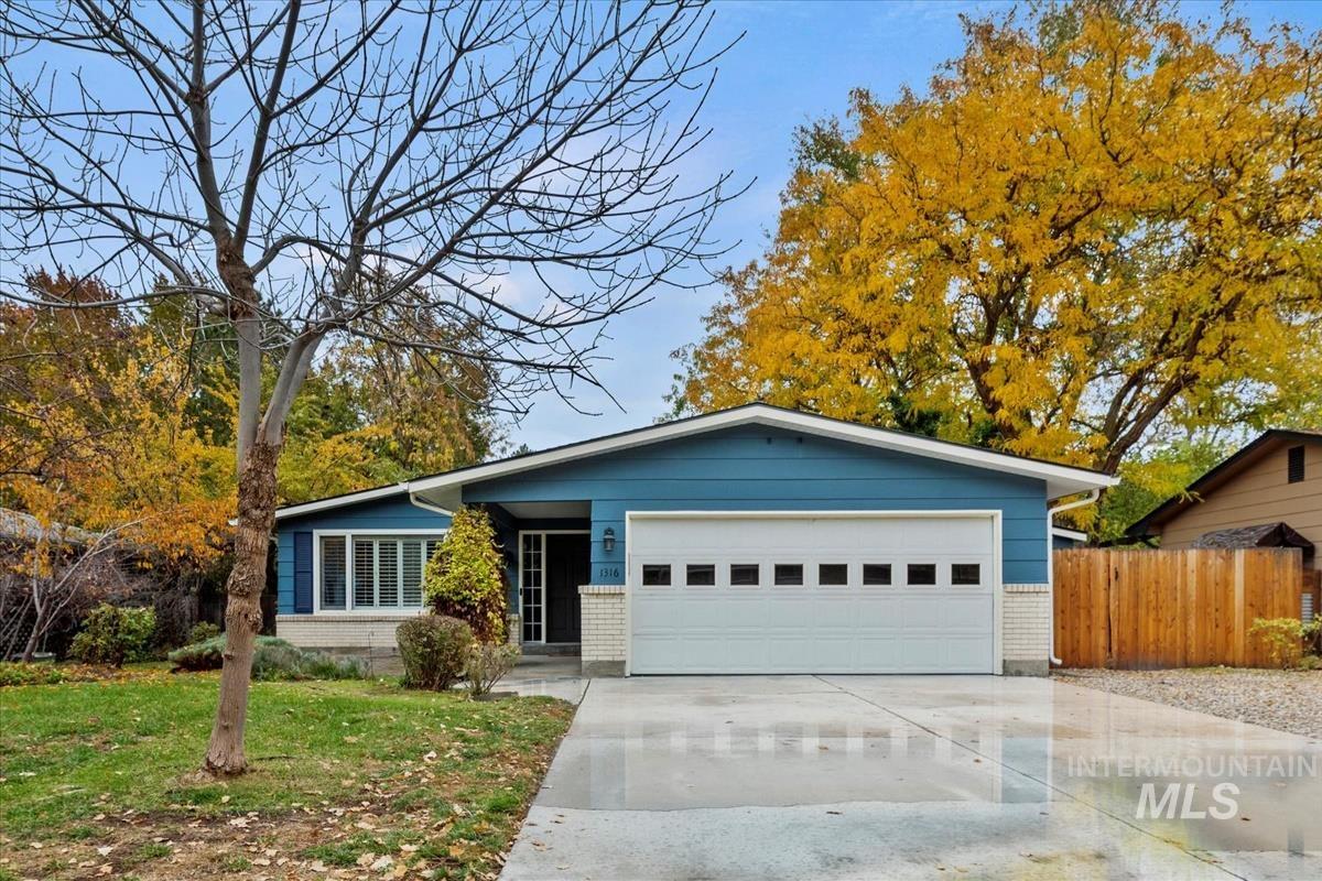 View of front facade with brick siding, concrete driveway, a front lawn, and an attached garage