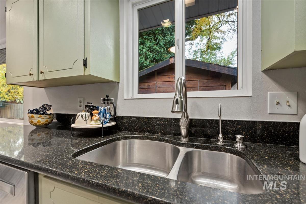 Kitchen view of dark stone counters and a textured wall