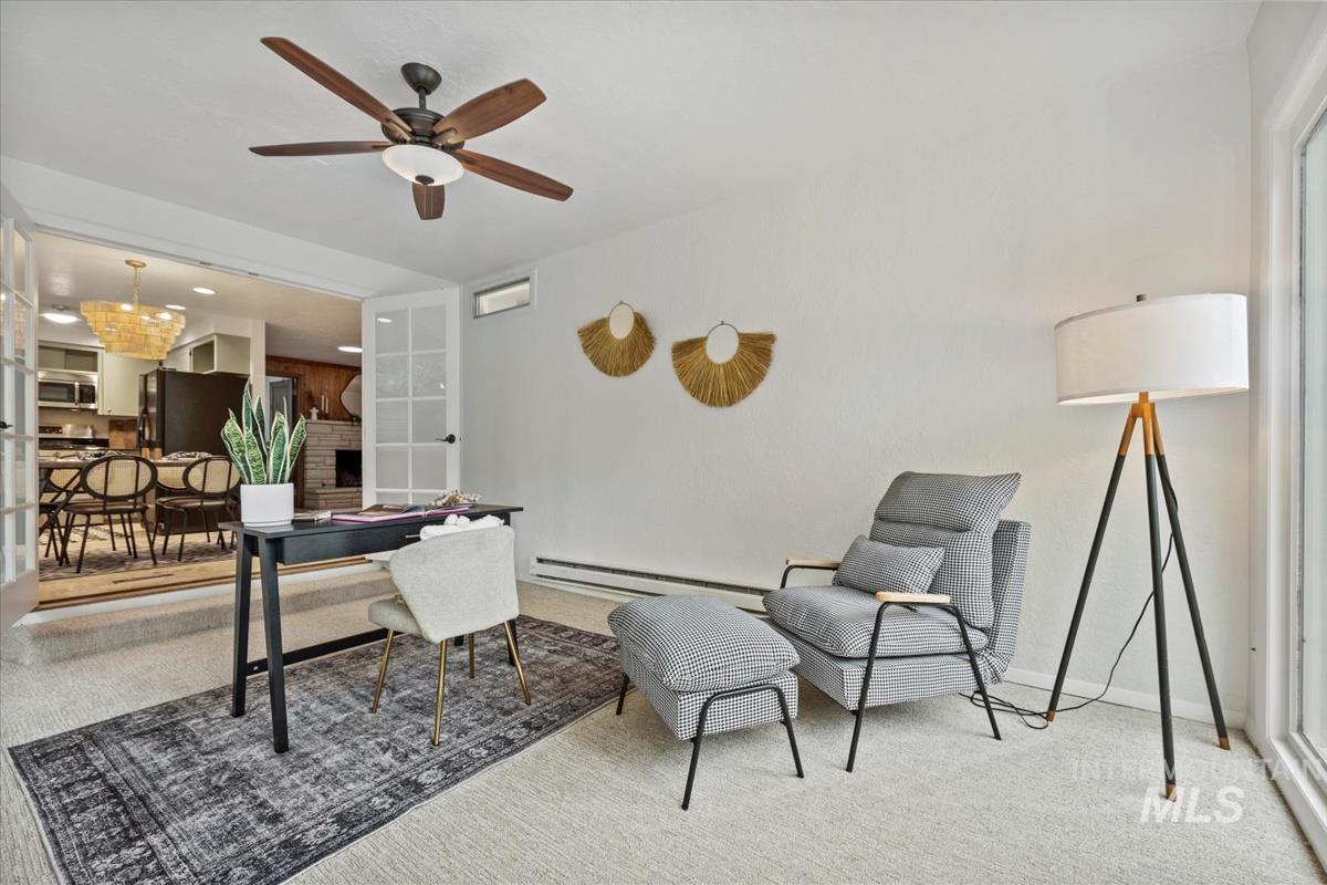 Carpeted office featuring a fireplace, baseboard heating, ceiling fan, and a chandelier