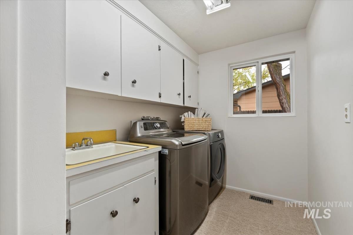 Laundry area with light colored carpet, washer and clothes dryer, and cabinet space